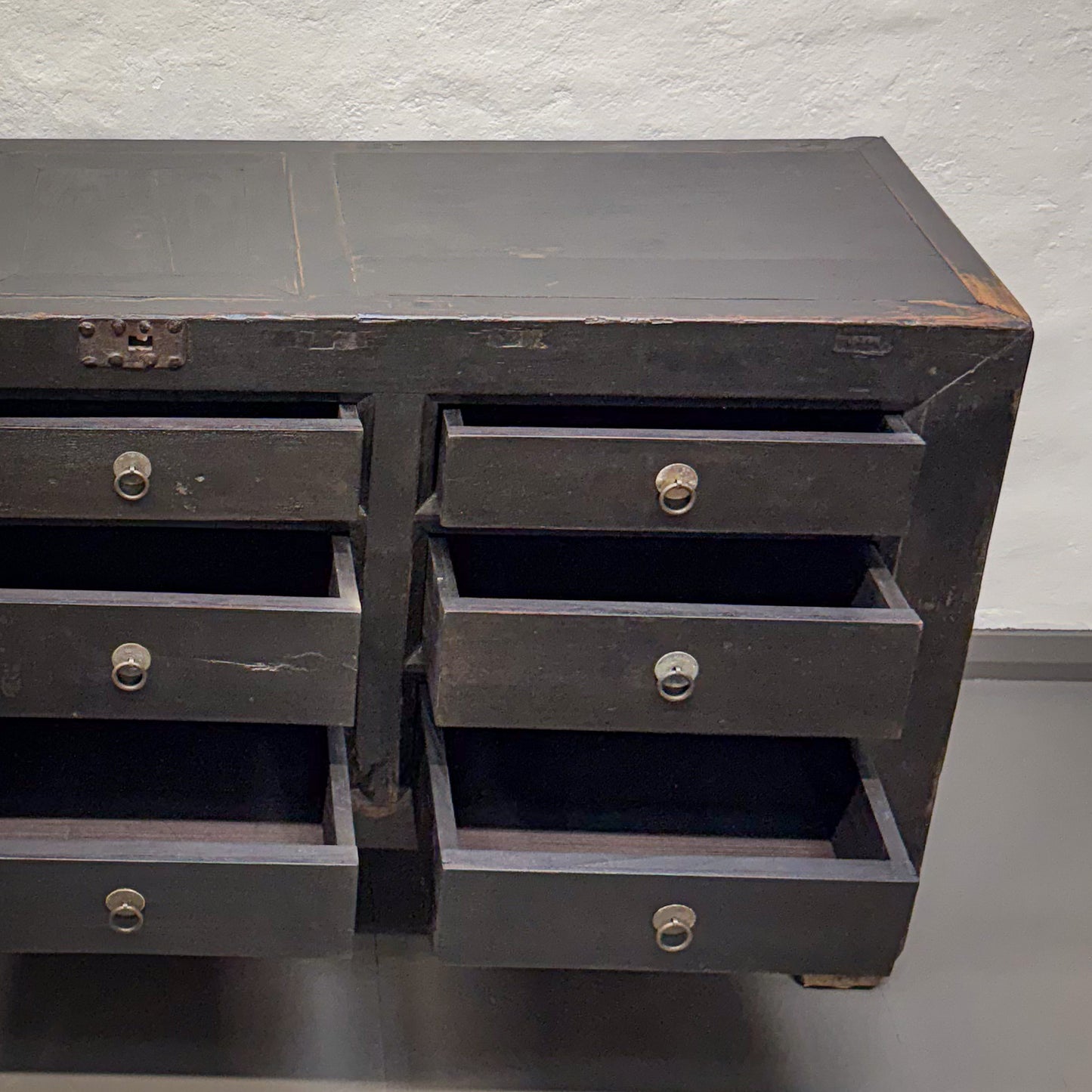 Dark wooden dresser with multiple drawers against a light gray background