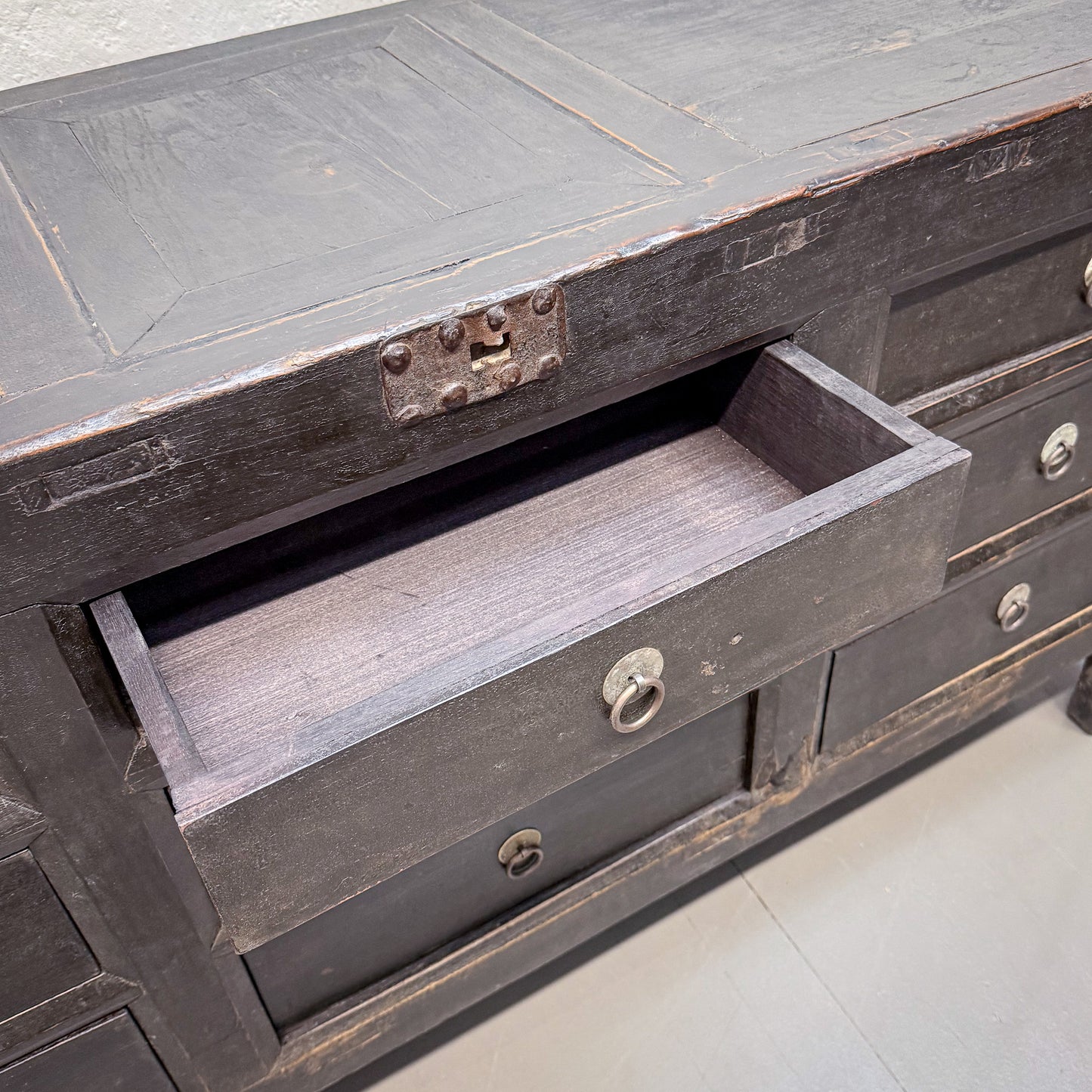 Vintage dark wood dresser with a drawer open on a light gray floor.
