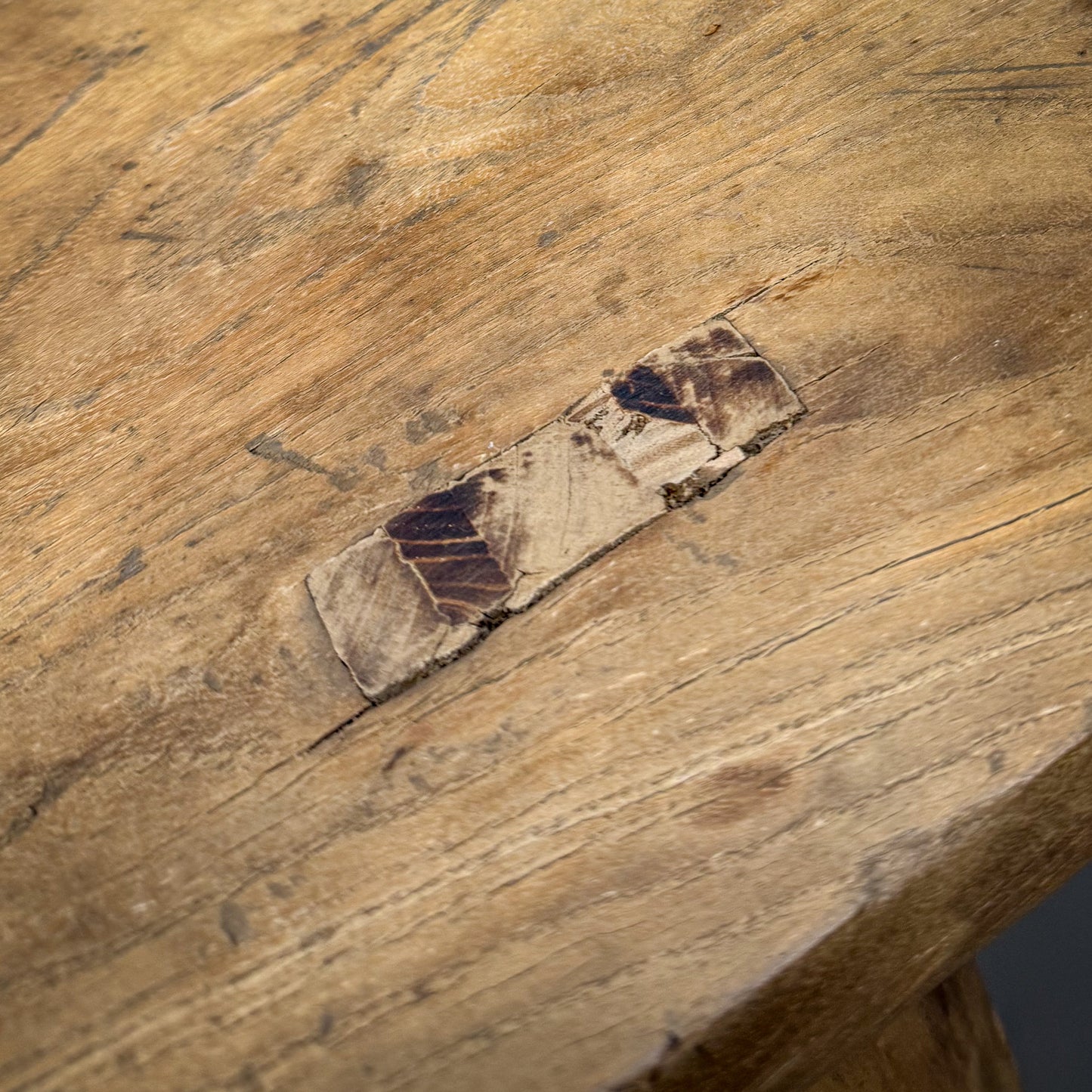 Close-up of a wooden surface with a crack and embedded piece of wood.