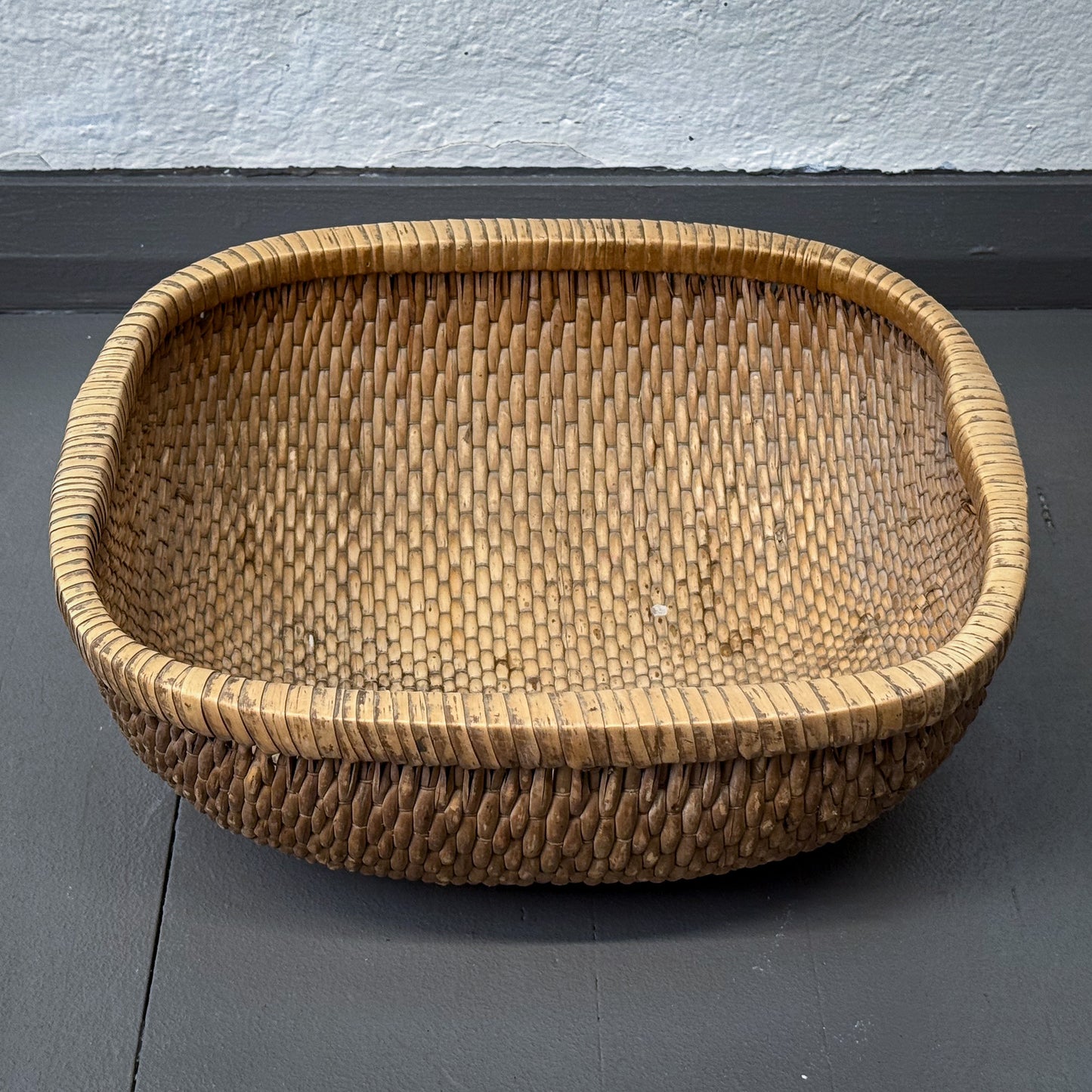 Woven basket on a gray surface with a light blue wall background