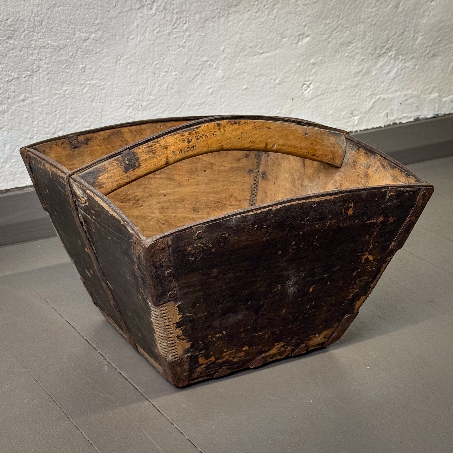 Vintage wooden box with a handle on a gray floor against a white wall