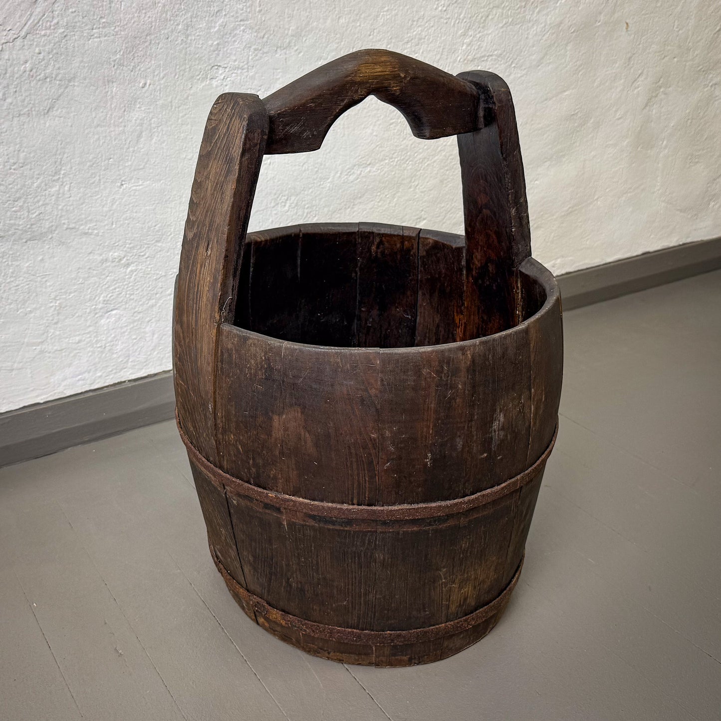 Wooden bucket with handle on a plain floor and wall background