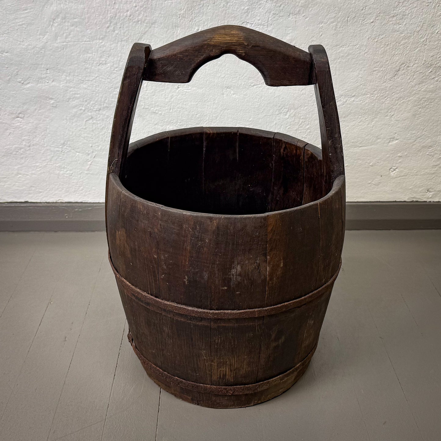 Wooden bucket with handles on a plain floor and wall background
