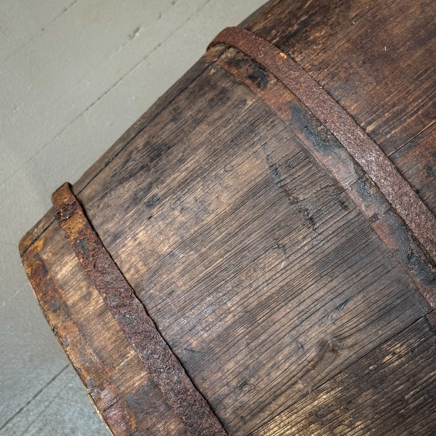 Close-up of an old wooden barrel with a metal band on a concrete floor.