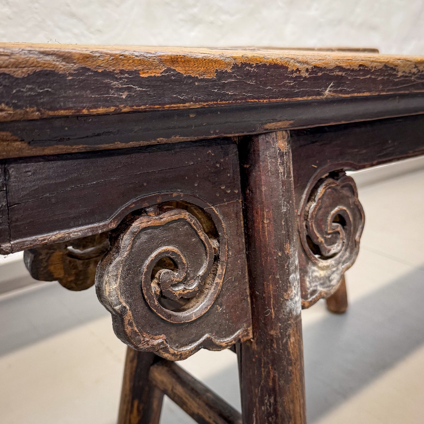 Close-up of an old wooden table with intricate carvings on a white background