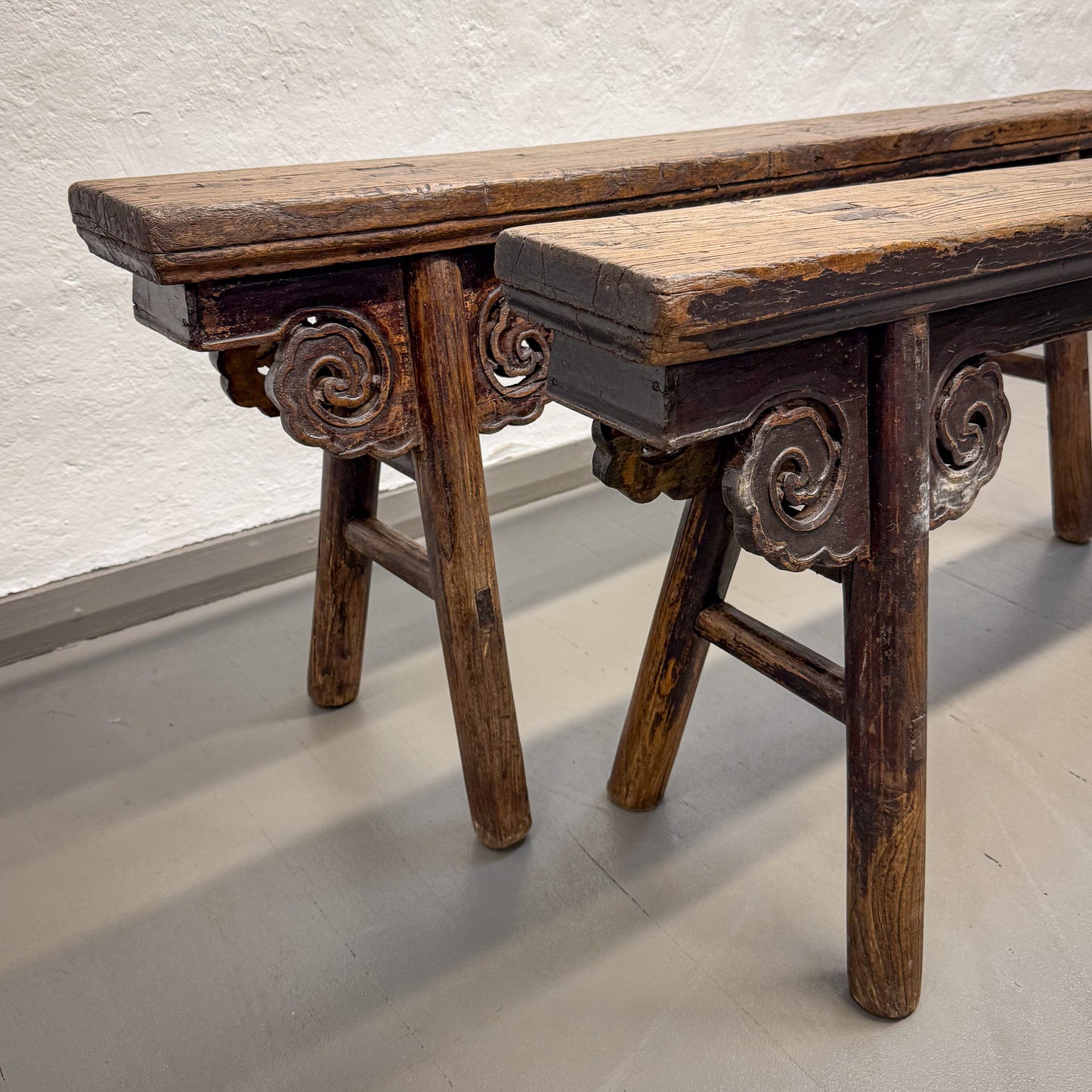 Two wooden benches with intricate carvings on a light background
