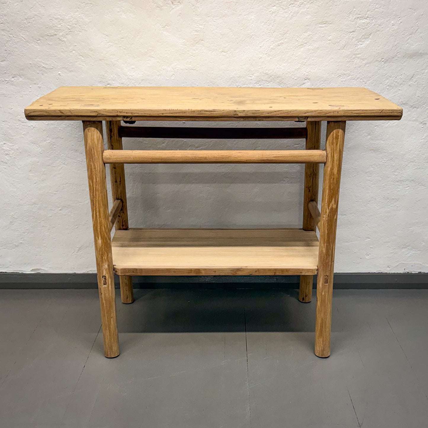 Wooden table with a shelf against a plain wall