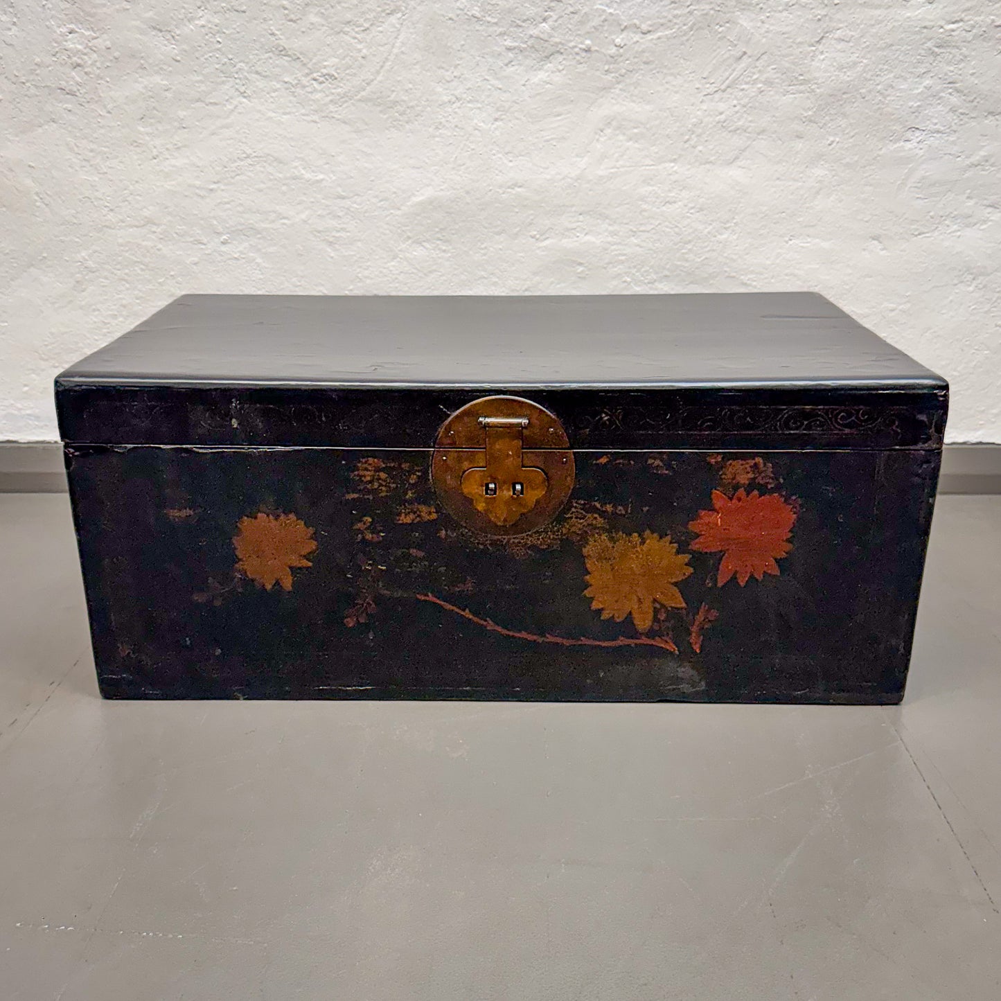 Decorative black trunk with floral designs on a light gray background