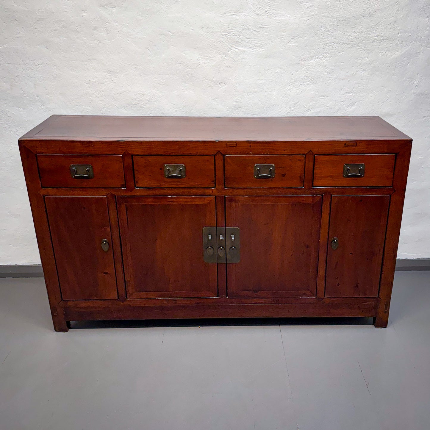 Wooden sideboard with four drawers and two doors on a plain background