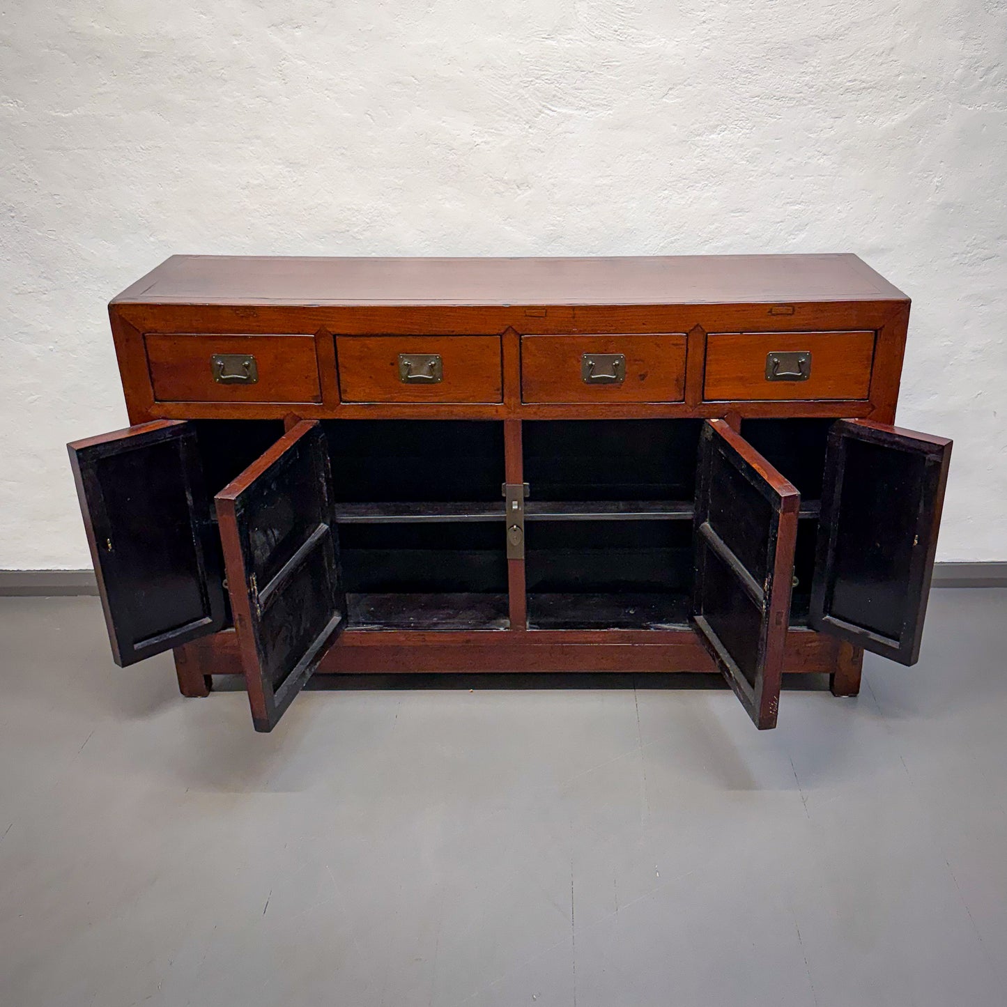 Wooden sideboard with open doors on a plain background