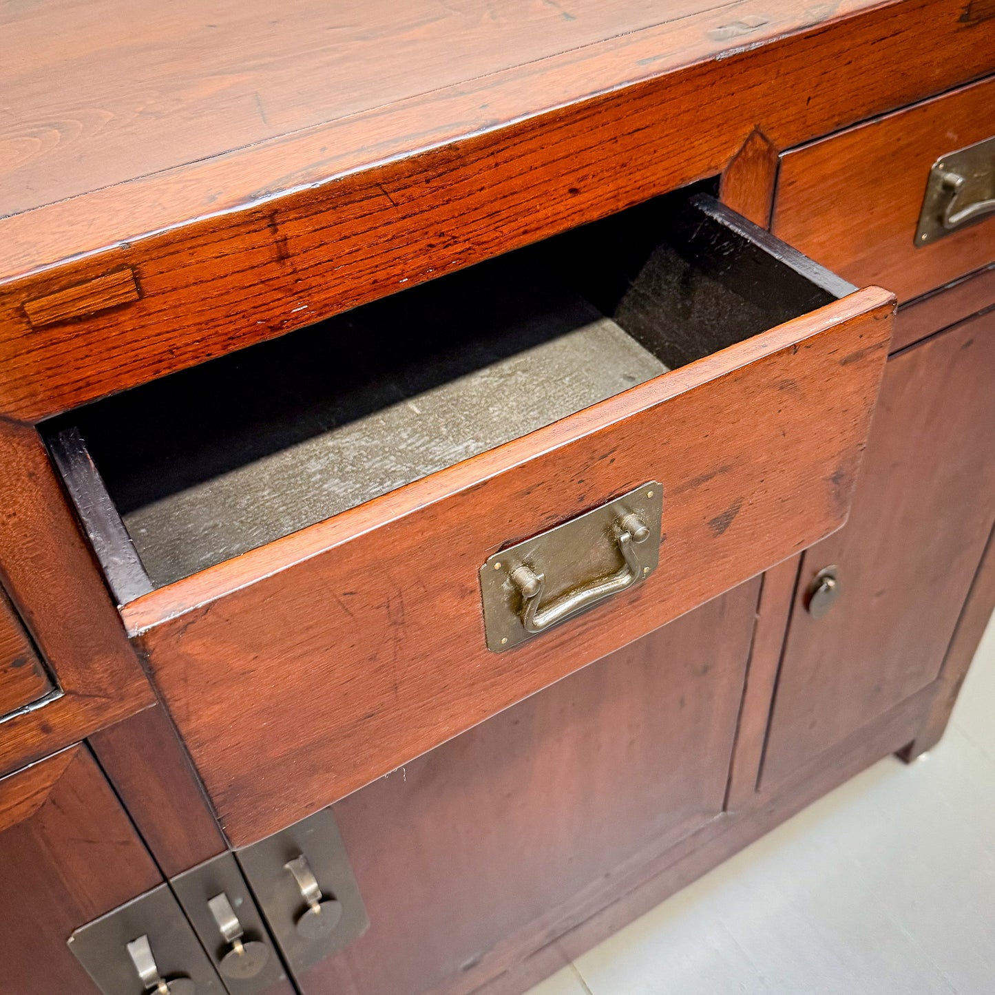 Wooden cabinet with an open drawer, showing brass handles.