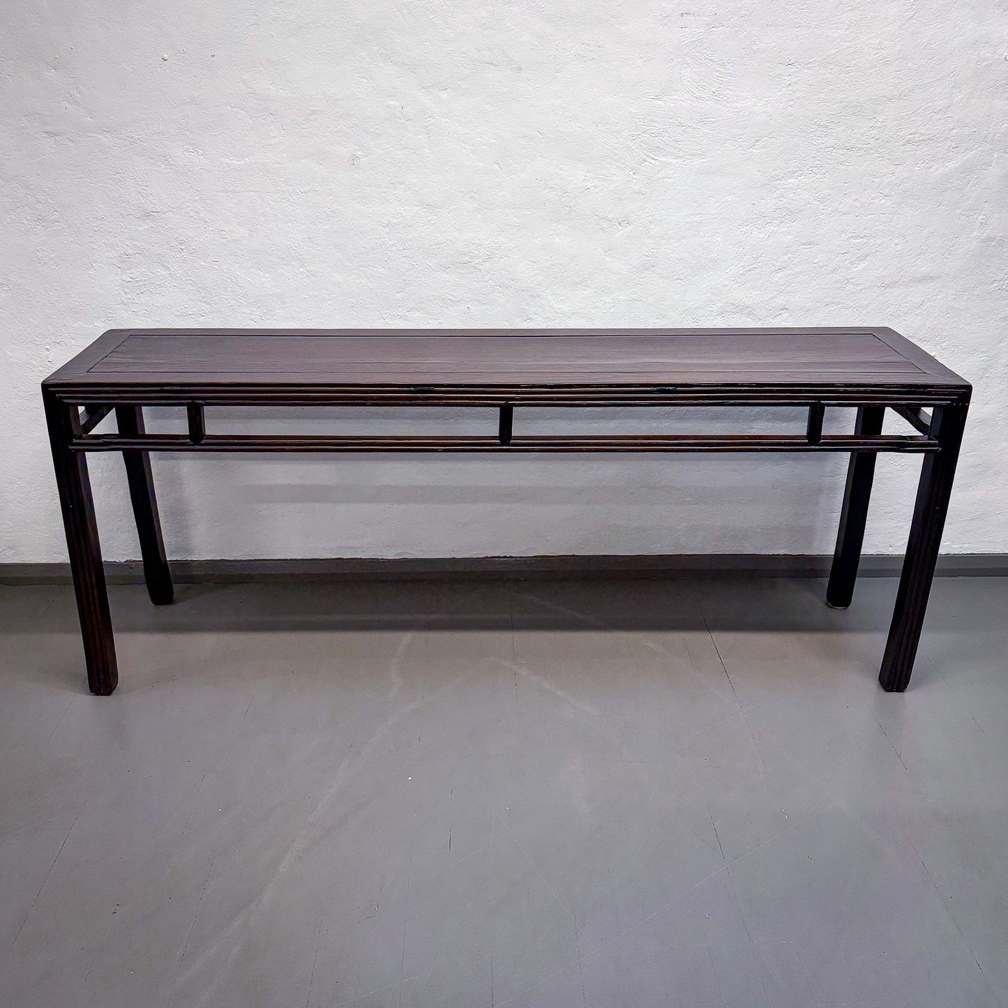 Dark wooden table against a white brick wall.