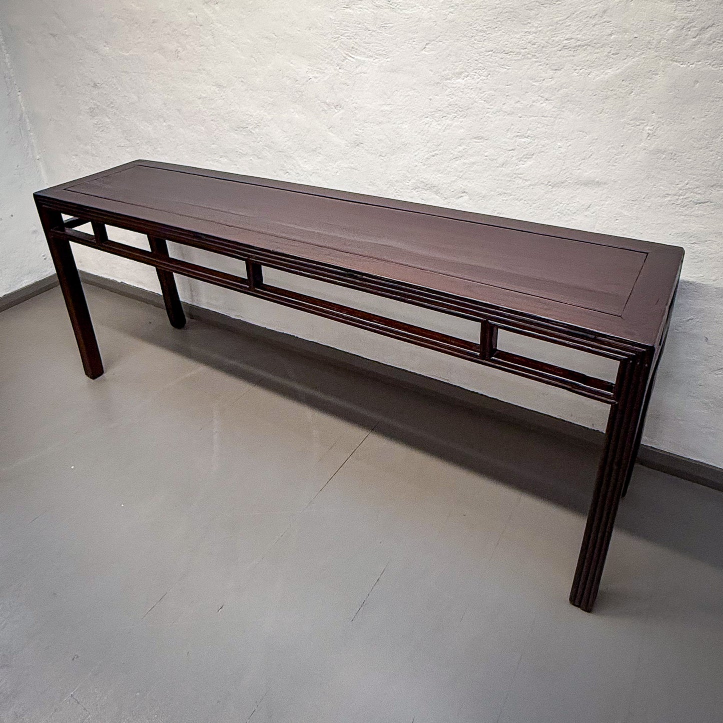 Wooden bench against a white textured wall