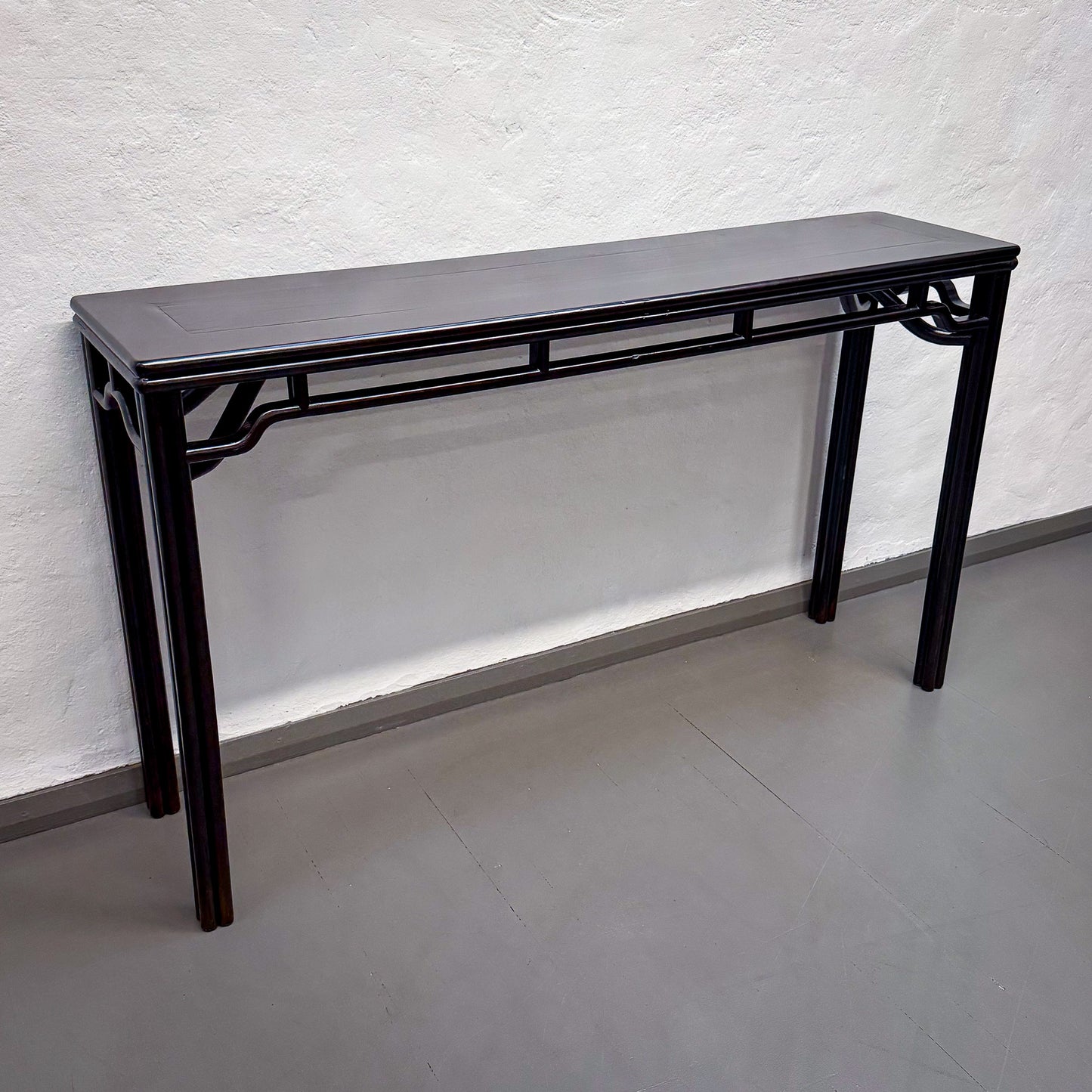 Black console table against a white textured wall.