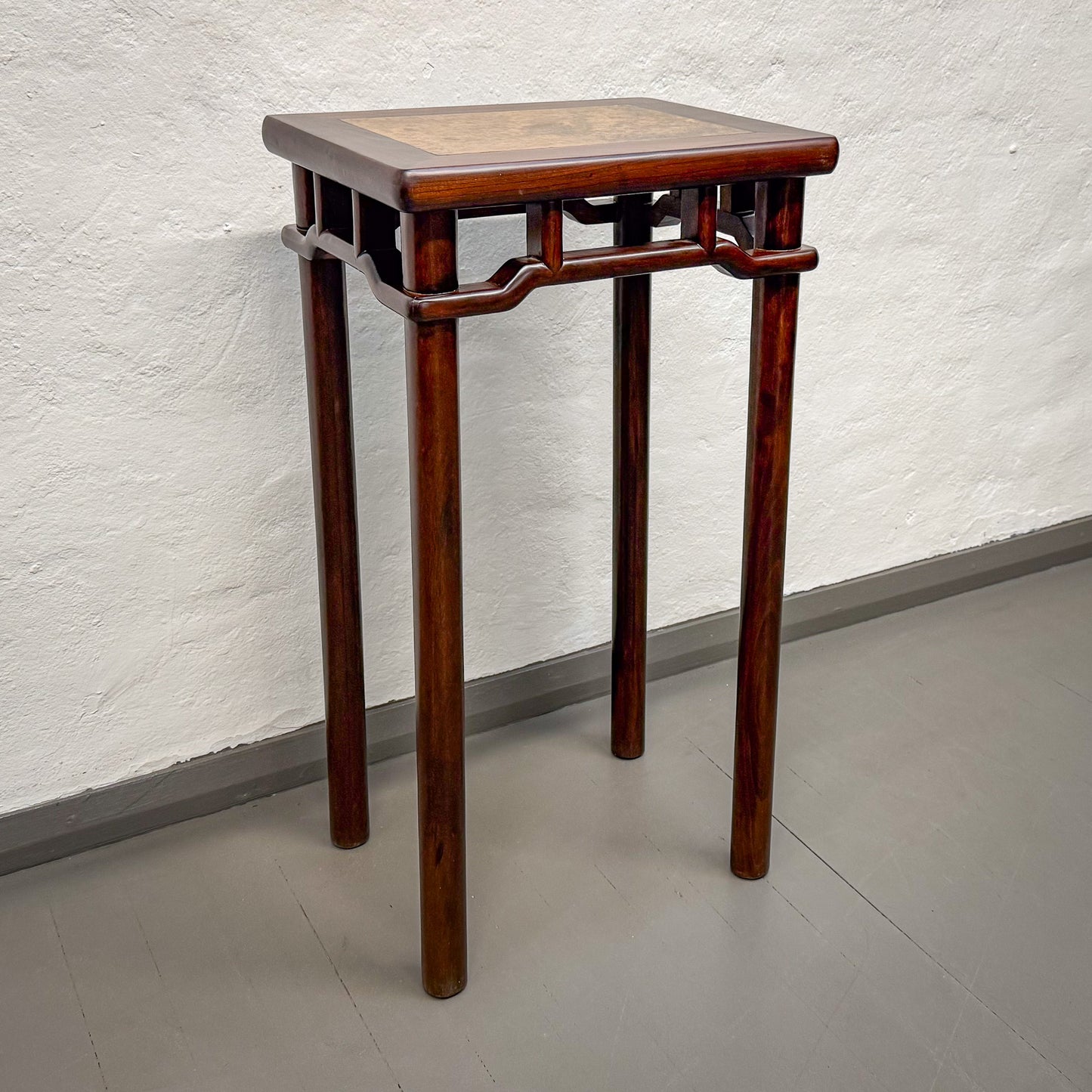 Wooden side table with a square top against a plain wall