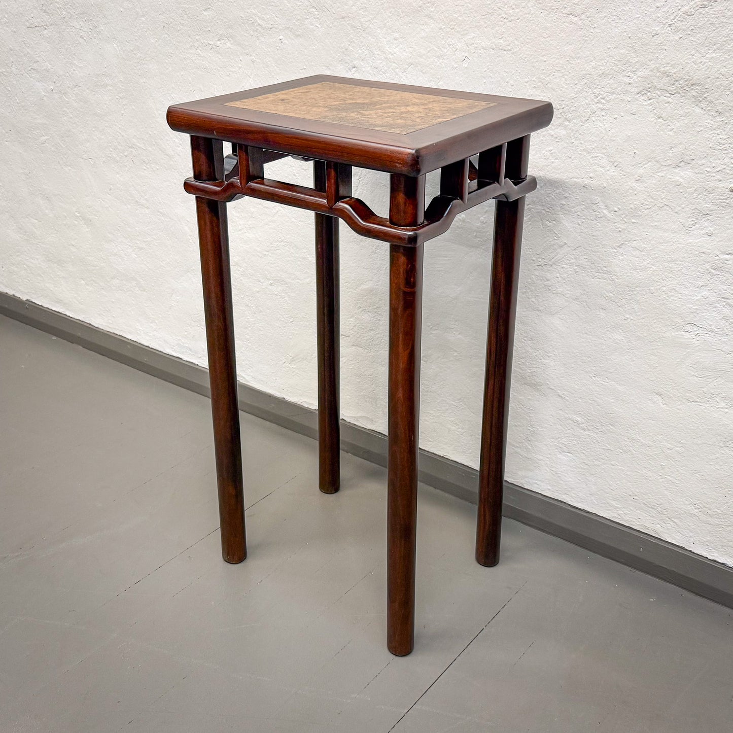Wooden side table with a square top against a light gray wall.