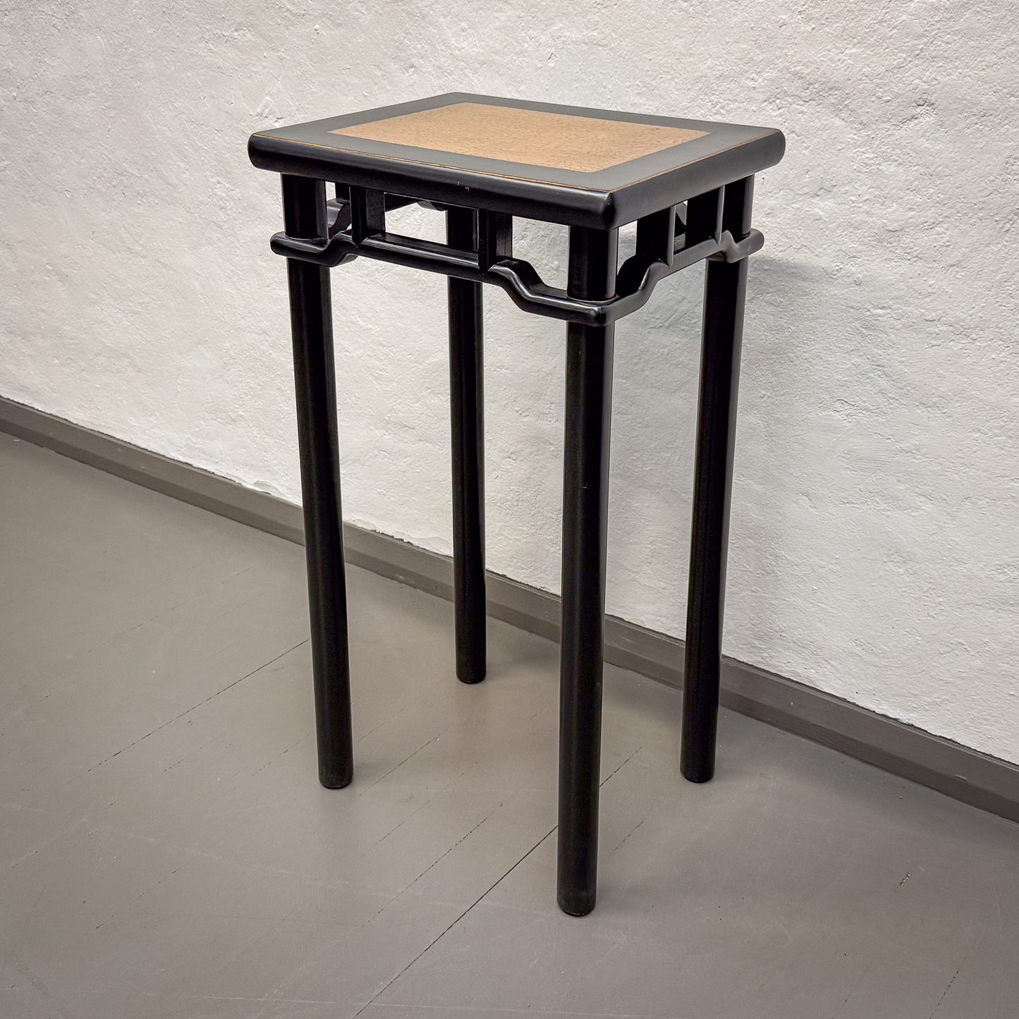 Black and brown side table against a textured wall.