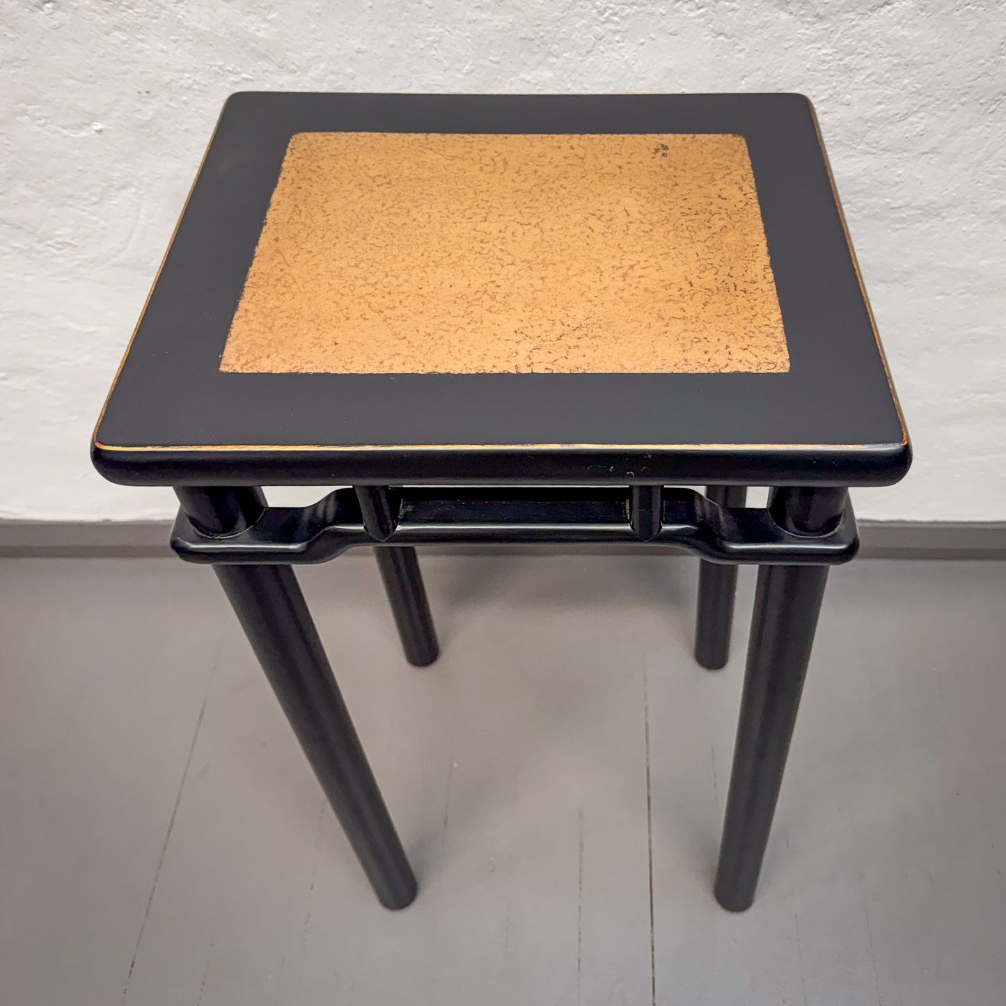 Small black table with a cork surface against a white wall.