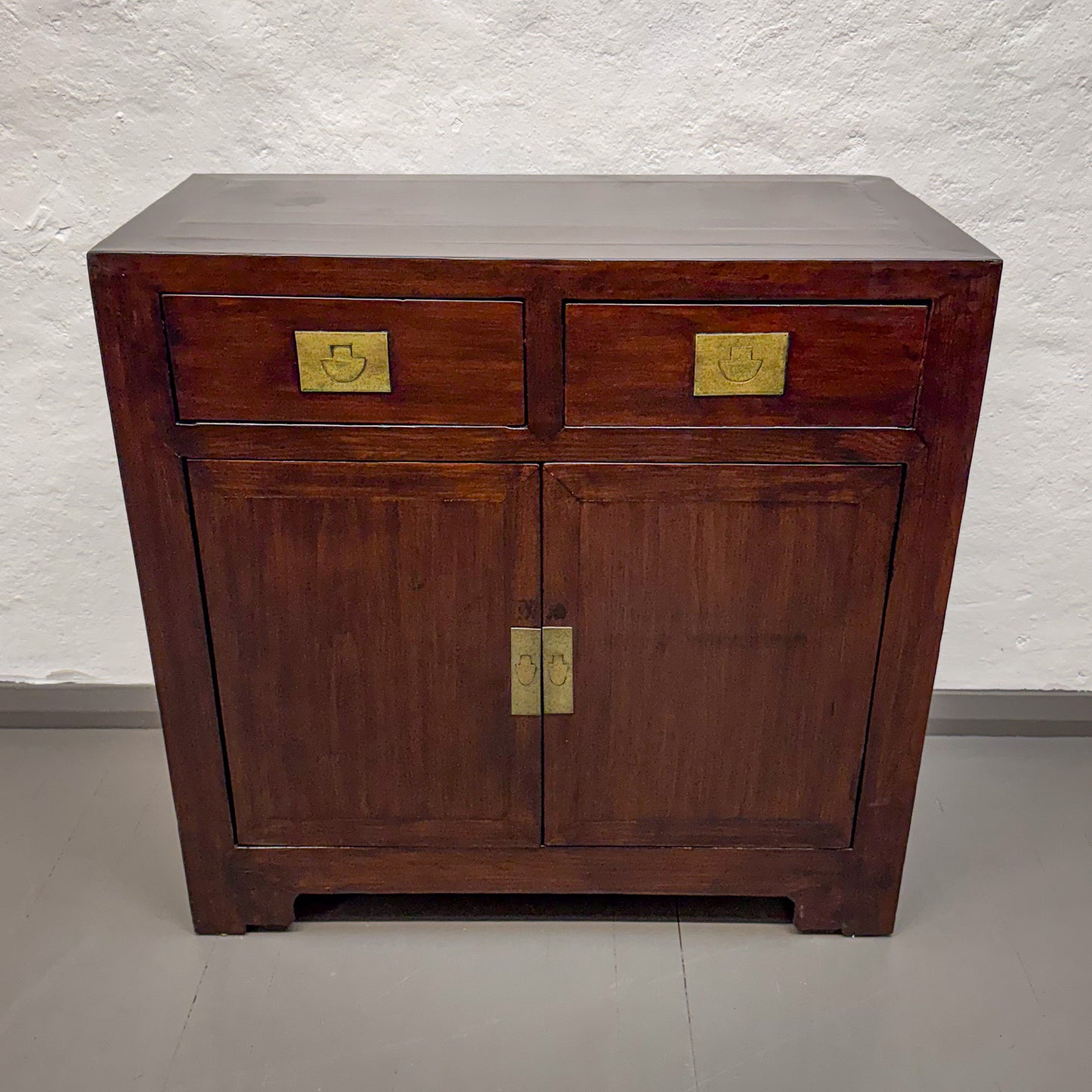 Wooden cabinet with brass handles on a plain background