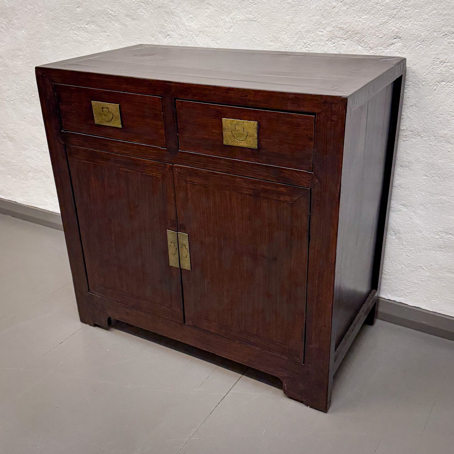Wooden cabinet with brass handles on a plain background