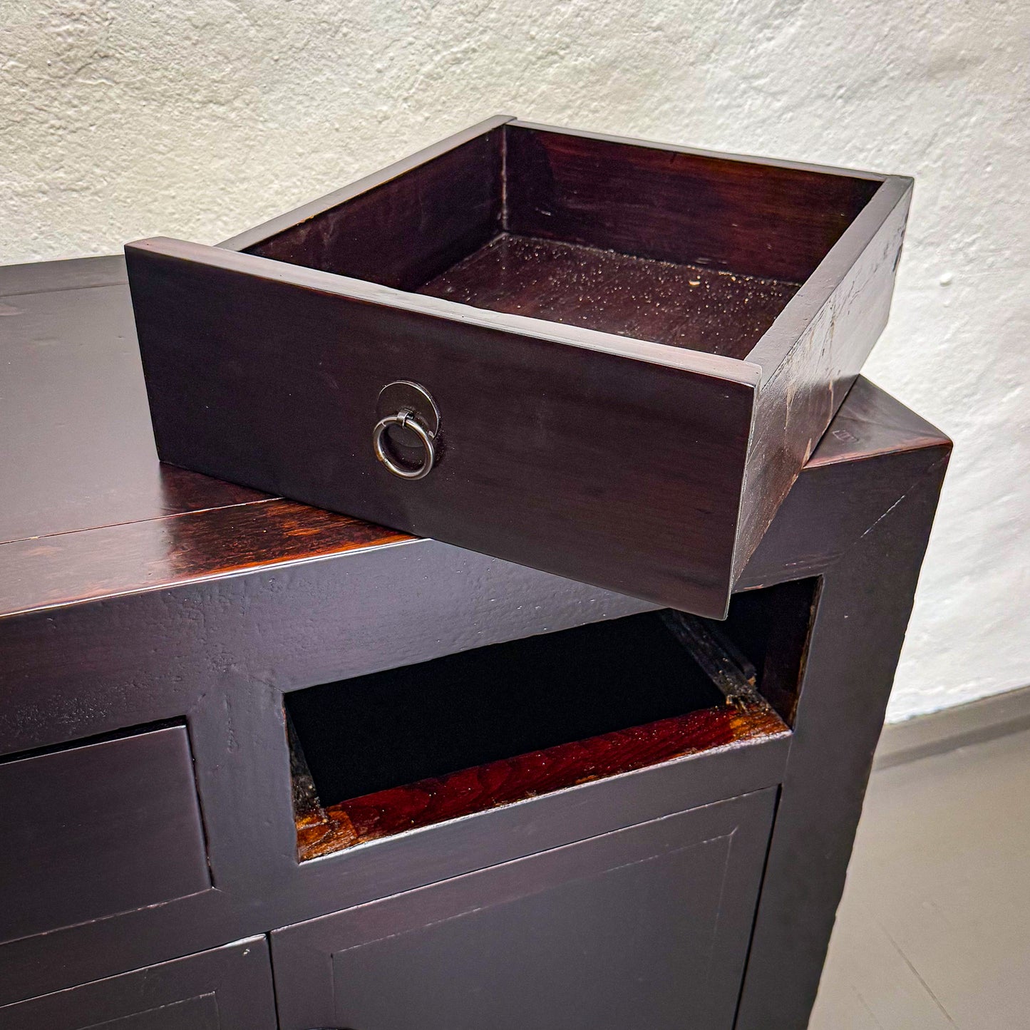 Dark wooden drawer set against a white wall