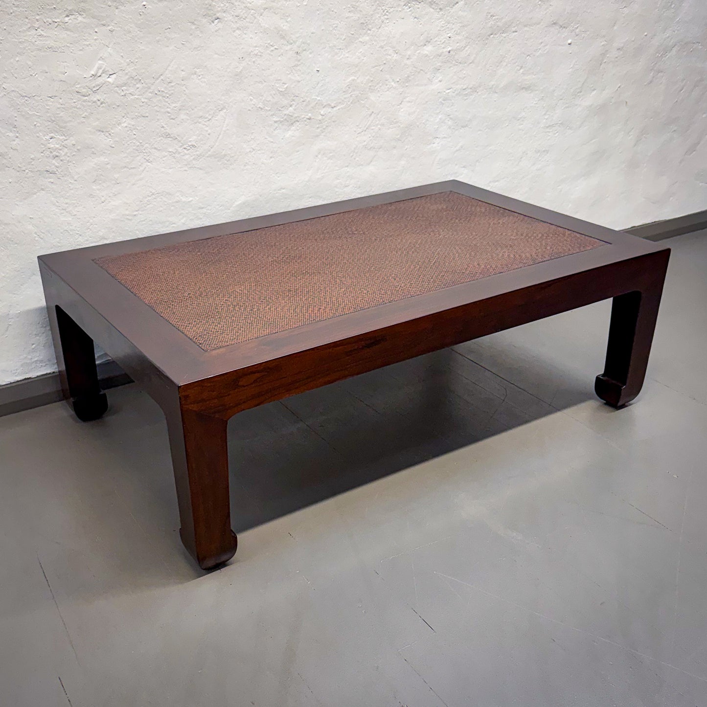 Wooden table with woven top against a white textured wall