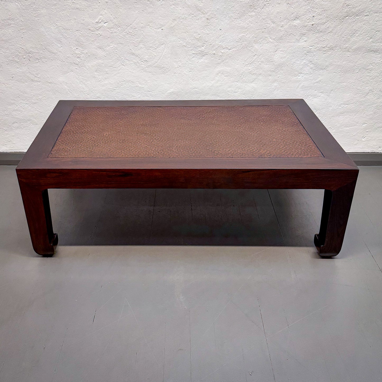 Wooden coffee table with woven top against a white wall