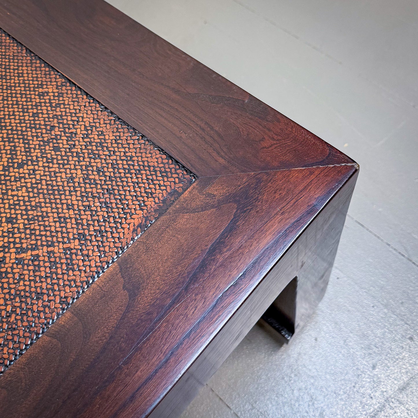 Close-up of a wooden bench with woven pattern on a light background