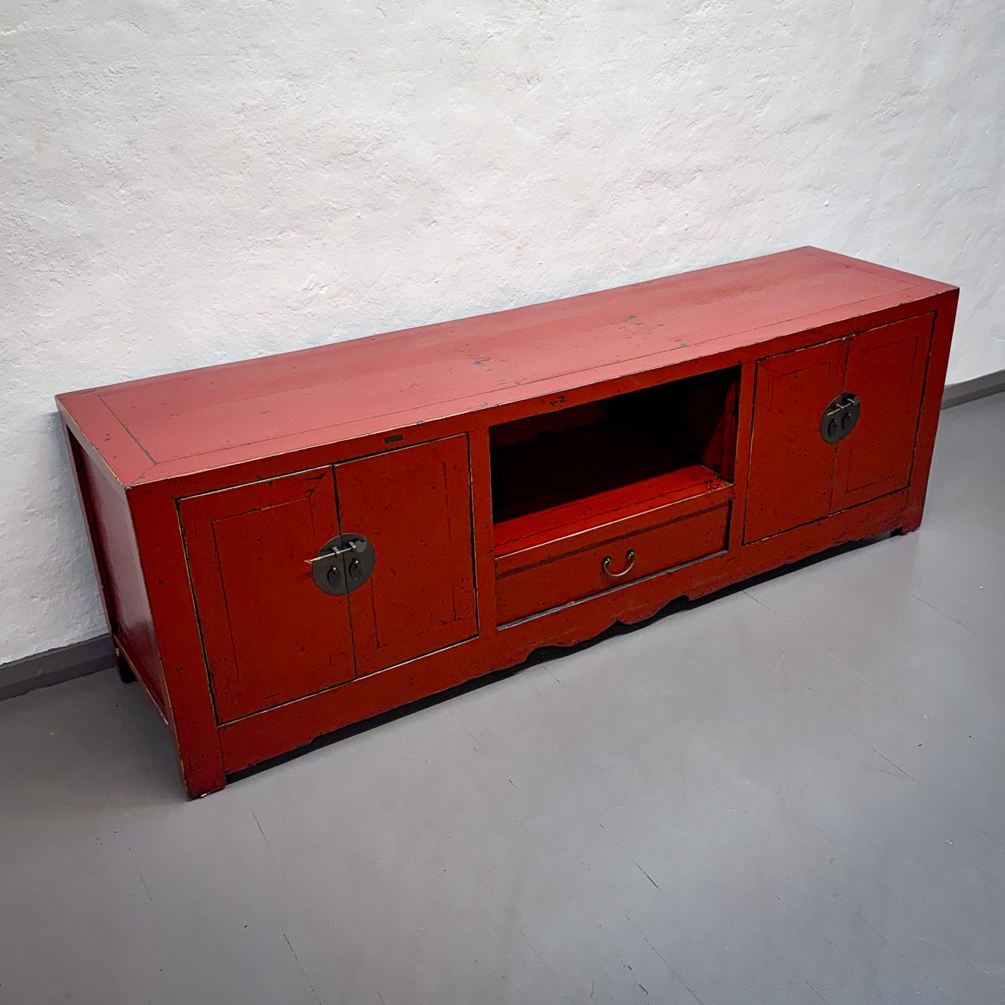 Red wooden TV stand against a white wall
