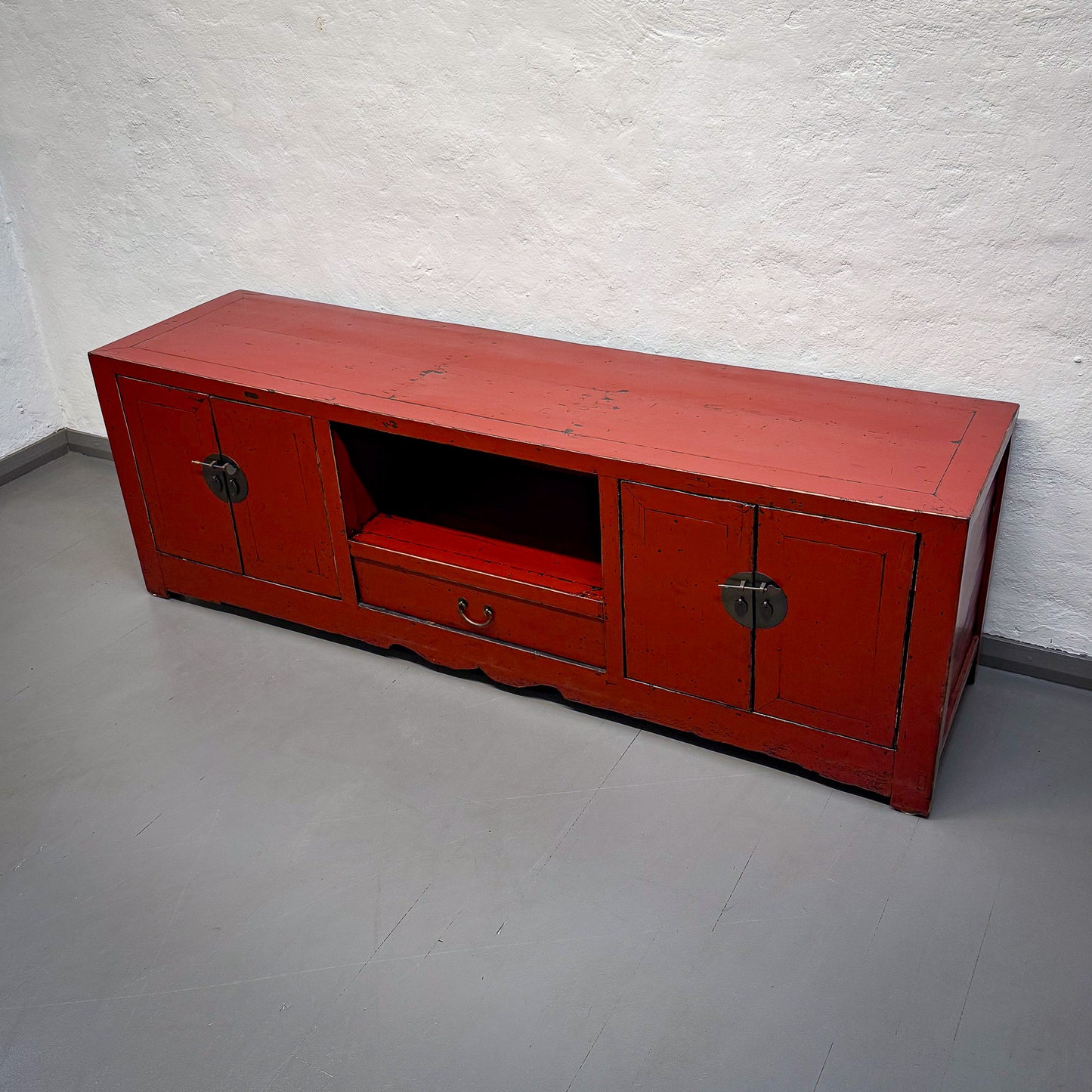 Red wooden TV stand against a white wall