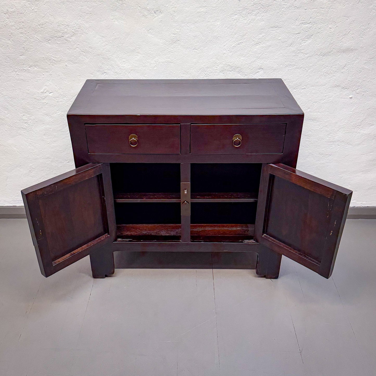 Wooden sideboard with open doors on a plain background