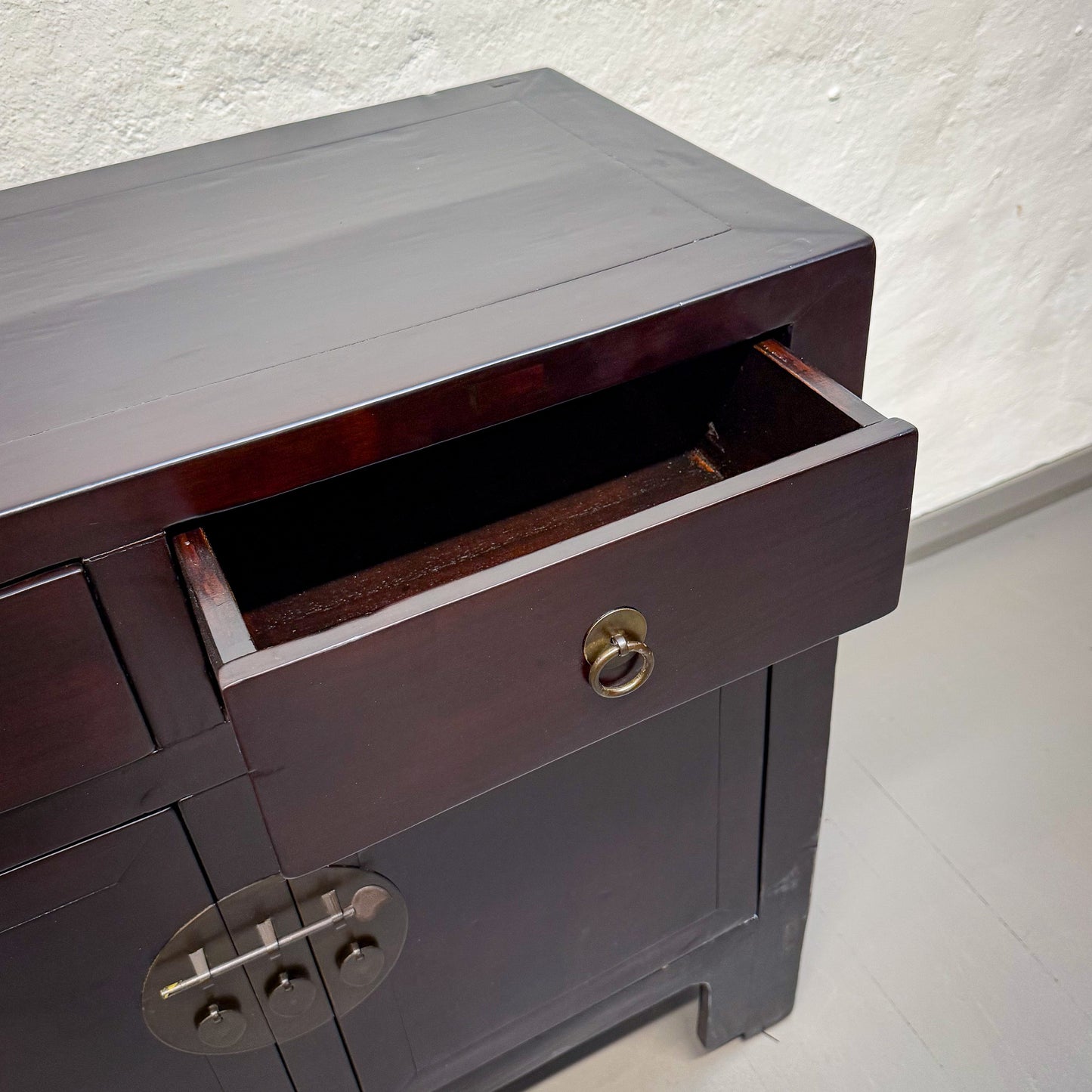 Dark wooden cabinet with a drawer open on a light background