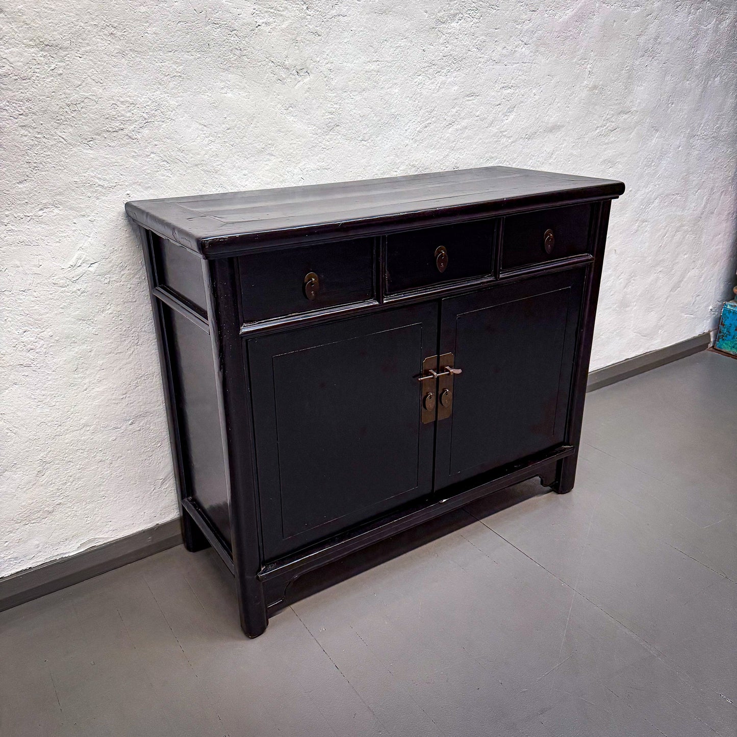 Black wooden sideboard against a white textured wall