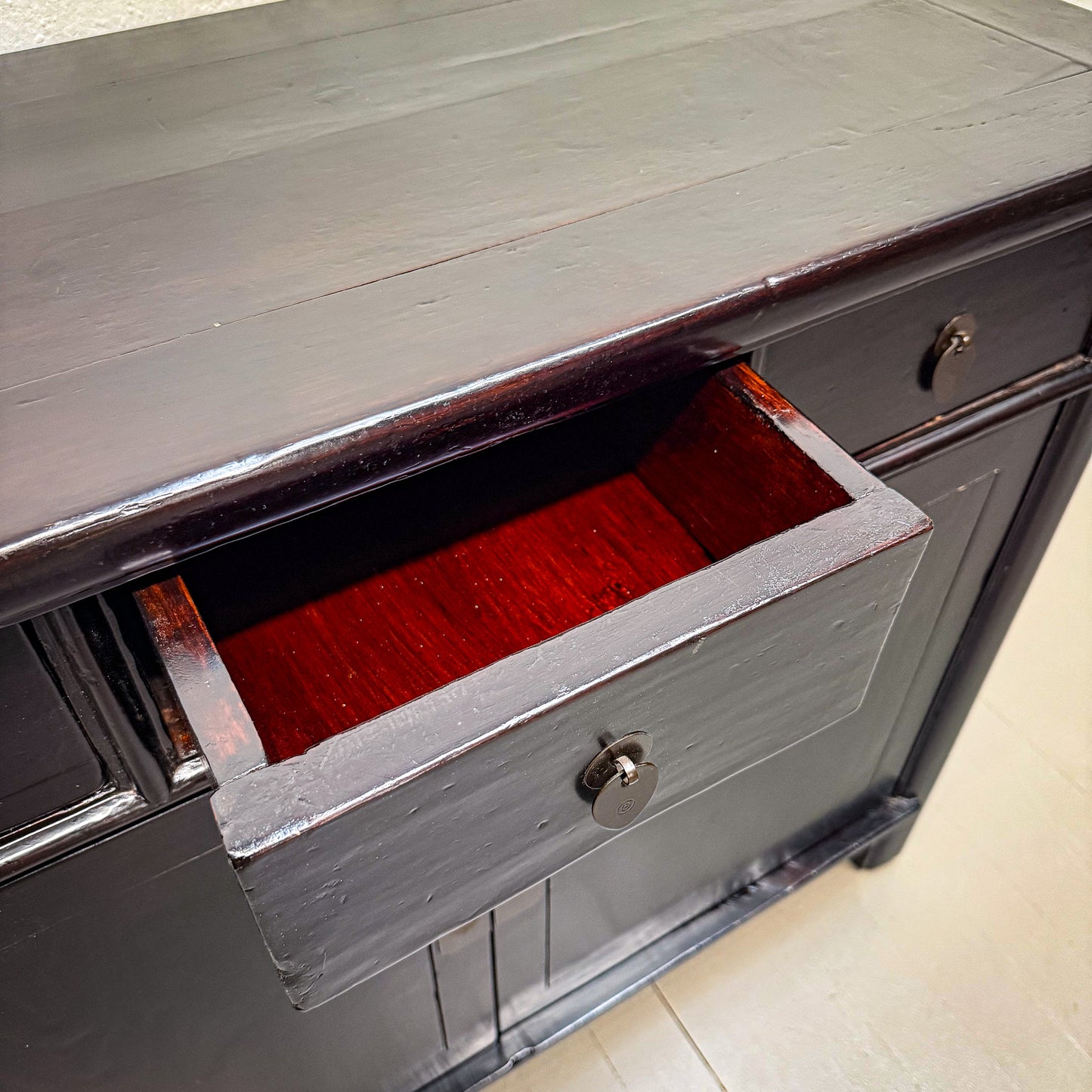 Gray wooden dresser with an open drawer revealing a red interior.