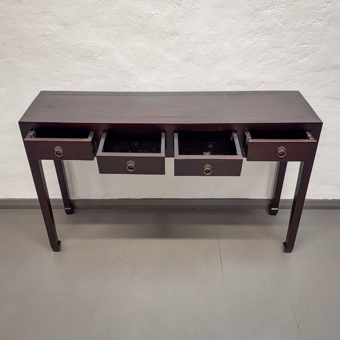 Dark wood console table with drawers against a light gray wall.
