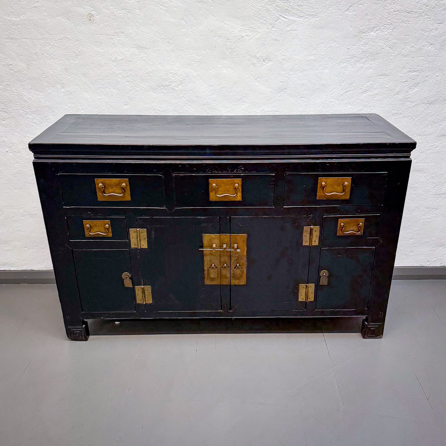 Black wooden dresser with gold hardware on a white background