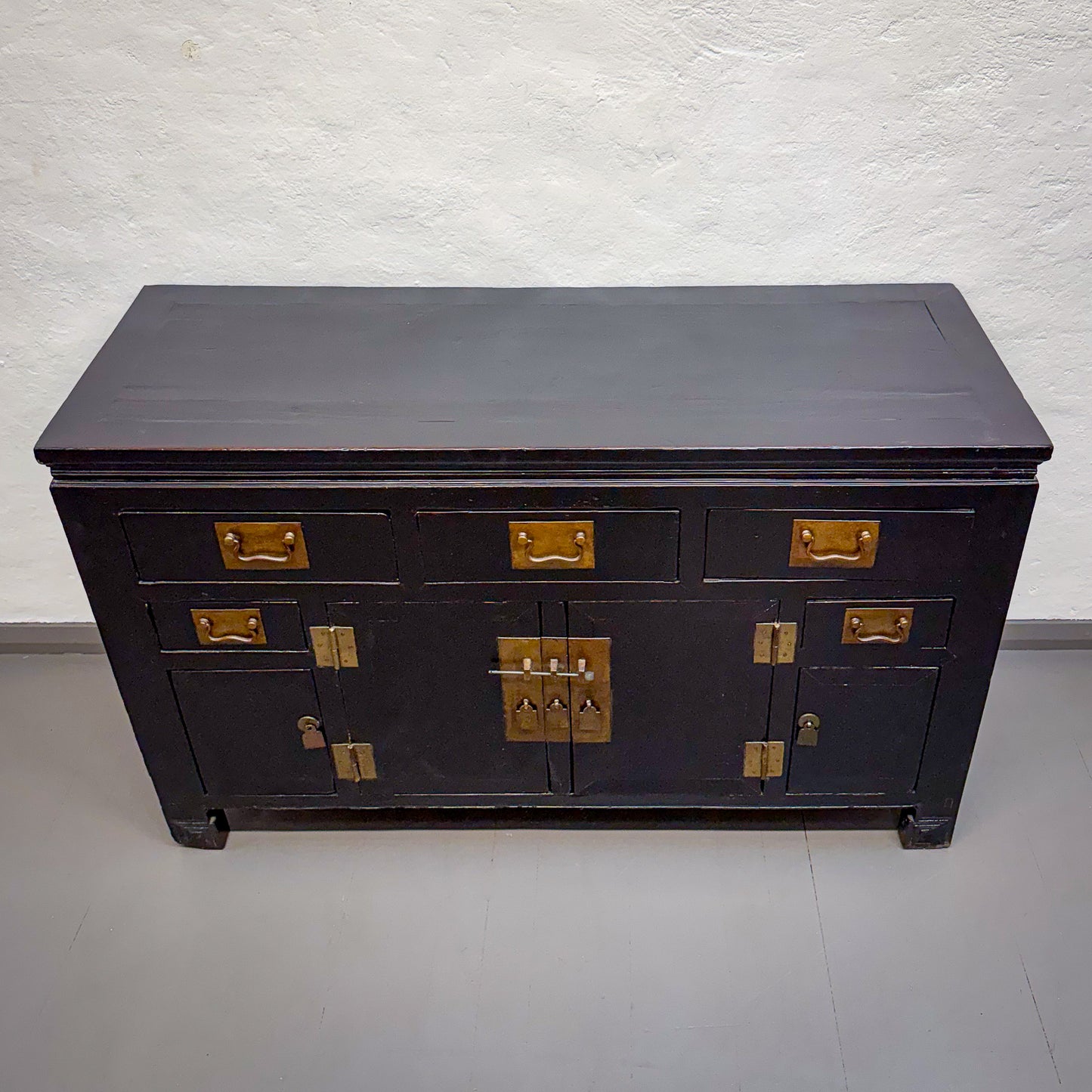 Black wooden dresser with gold accents on a white background