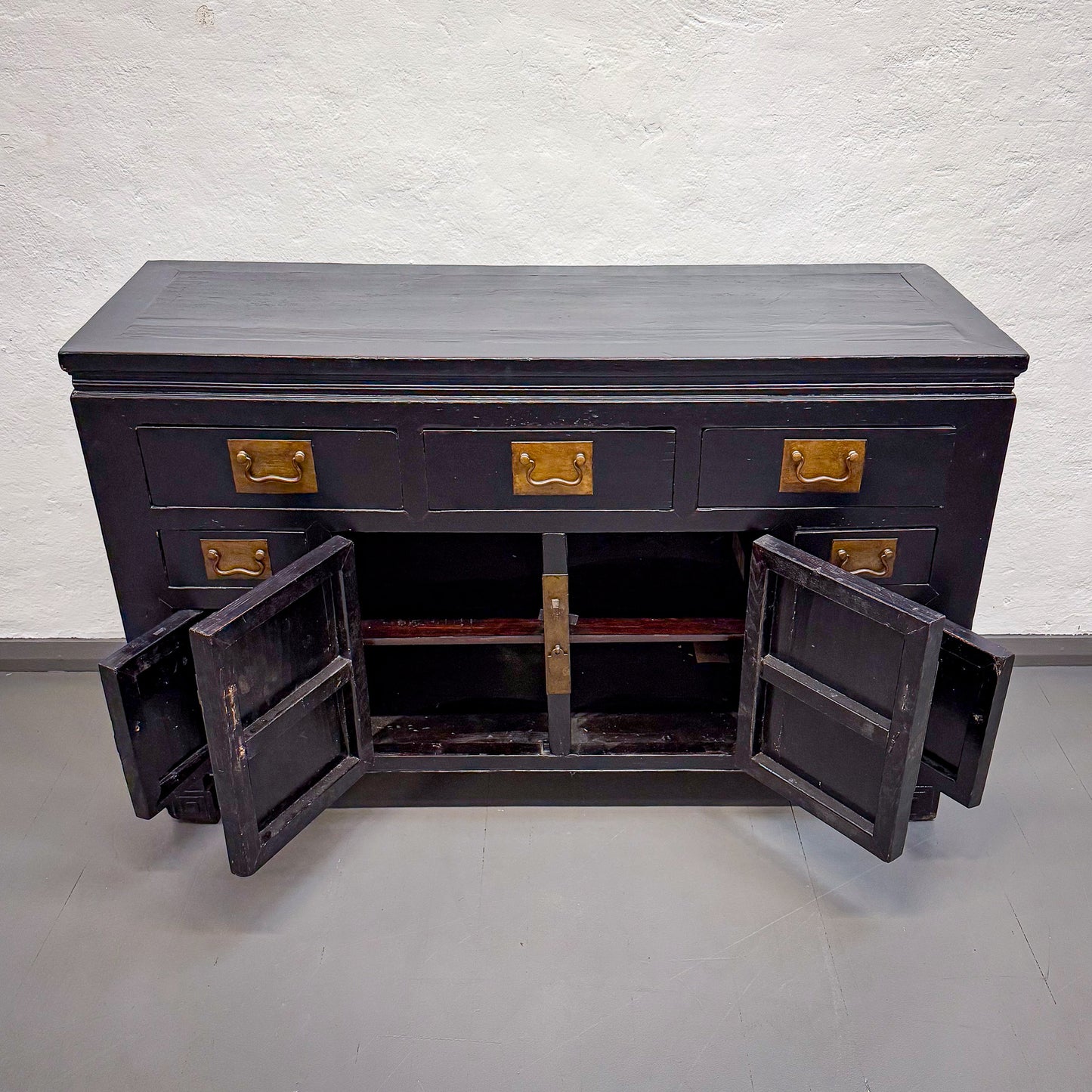 Black wooden cabinet with gold handles on a white background