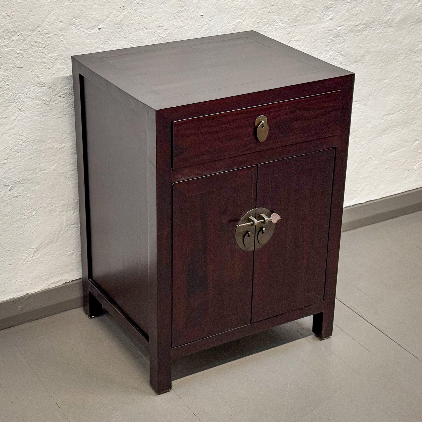 Dark wooden cabinet with a single drawer and two doors on a light gray floor.