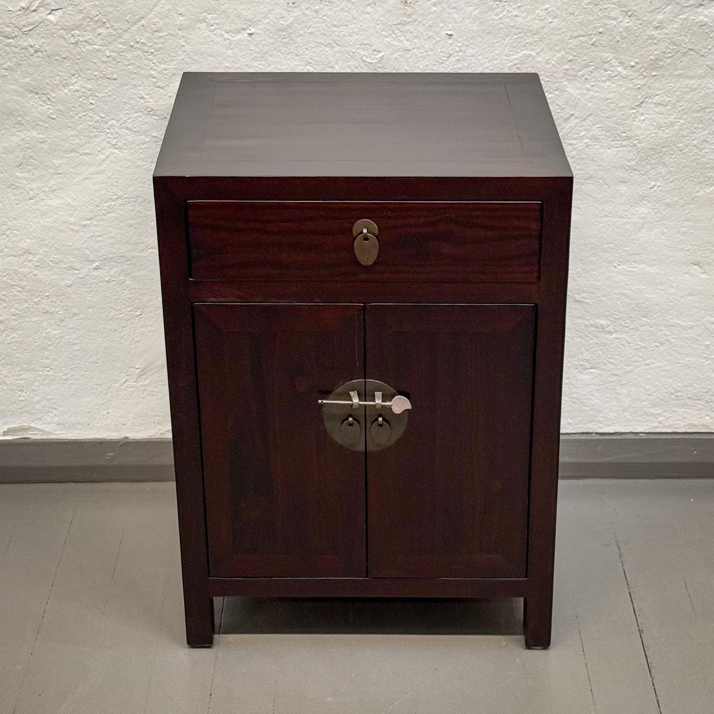 Wooden cabinet with a single drawer and a door on a plain background