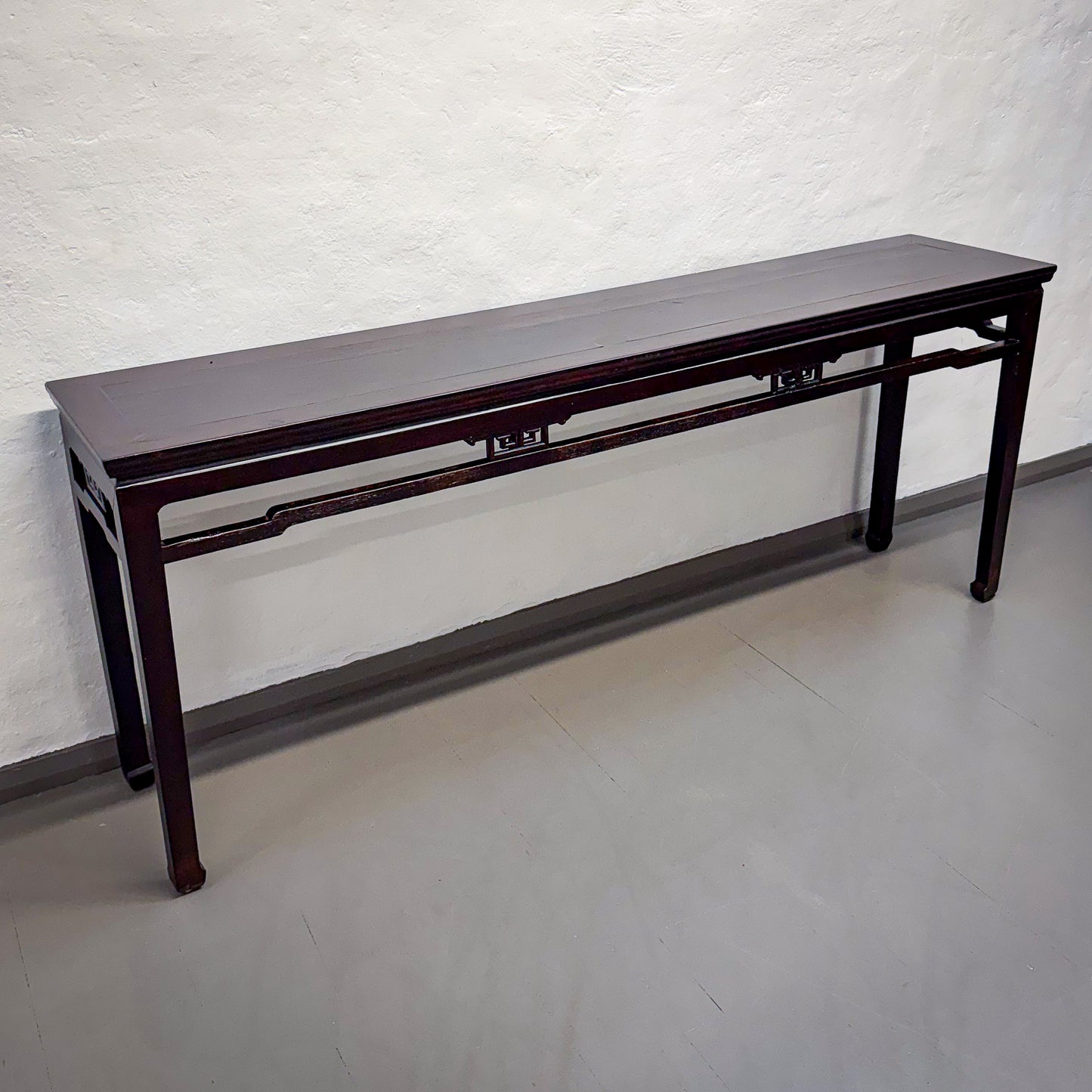 Long wooden table against a white brick wall.
