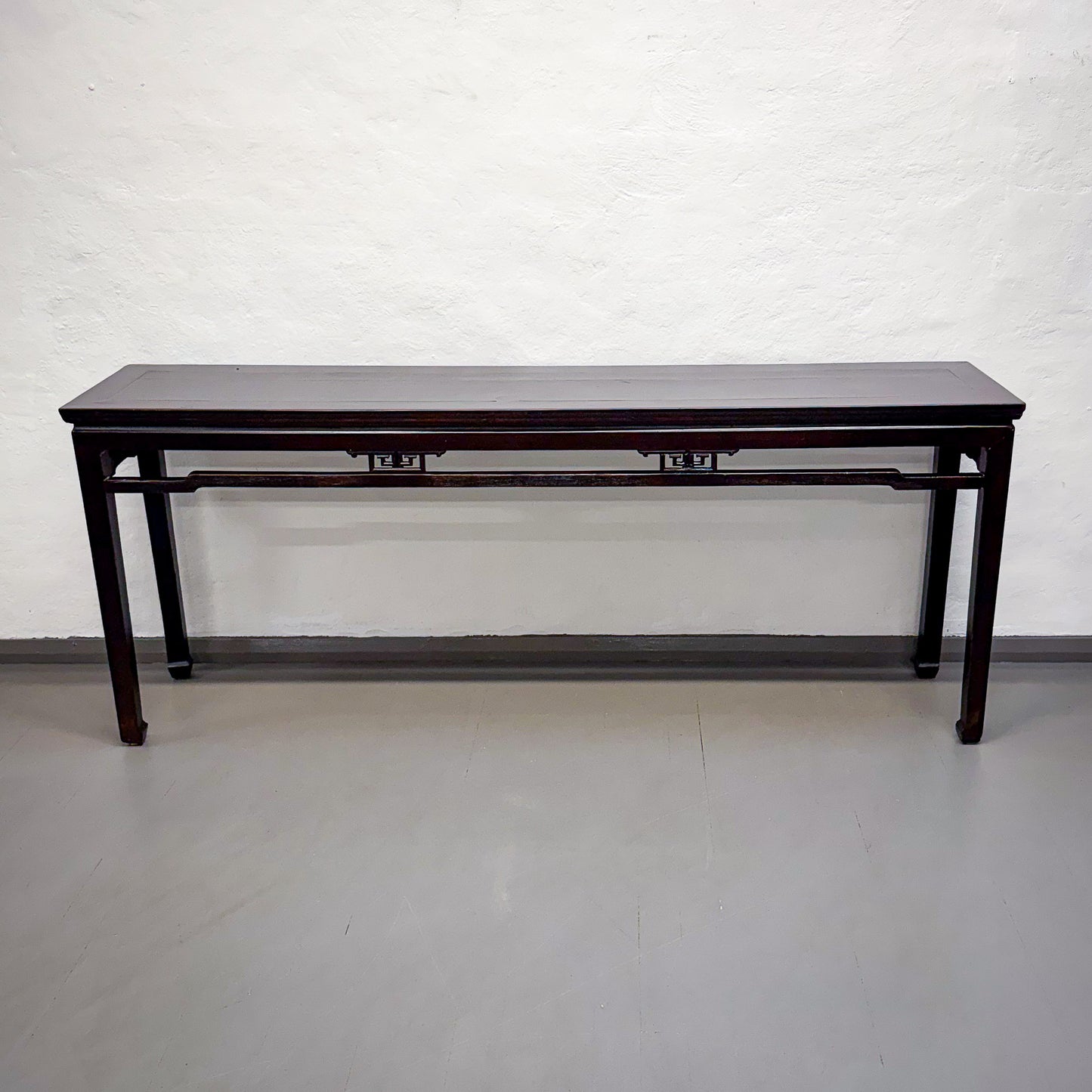 Long dark wooden table against a white wall