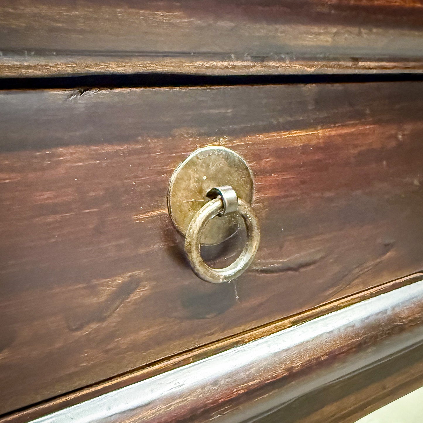 Close-up of a wooden surface with a metal ring handle.