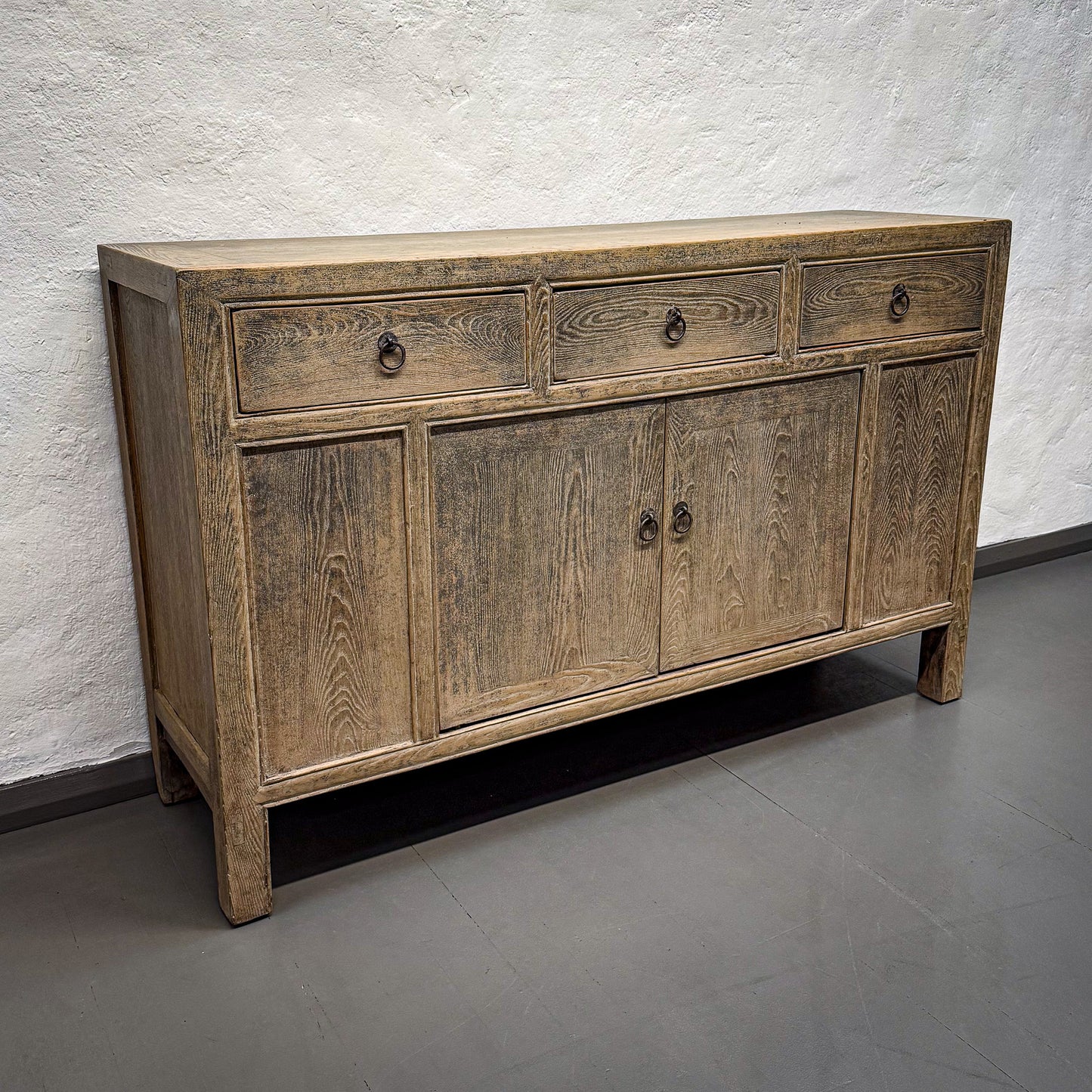 Wooden sideboard with drawers and doors against a white wall.