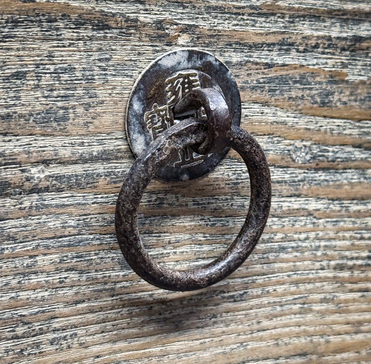Decorative metal ring with Chinese characters on a wooden surface