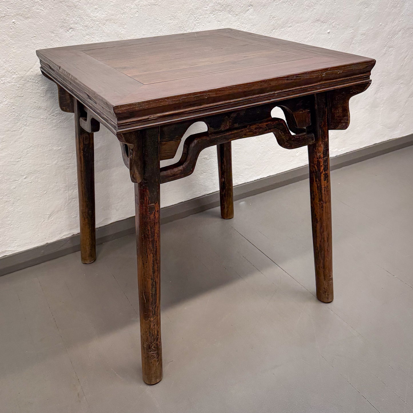 Wooden table with a textured surface on a plain floor and wall background