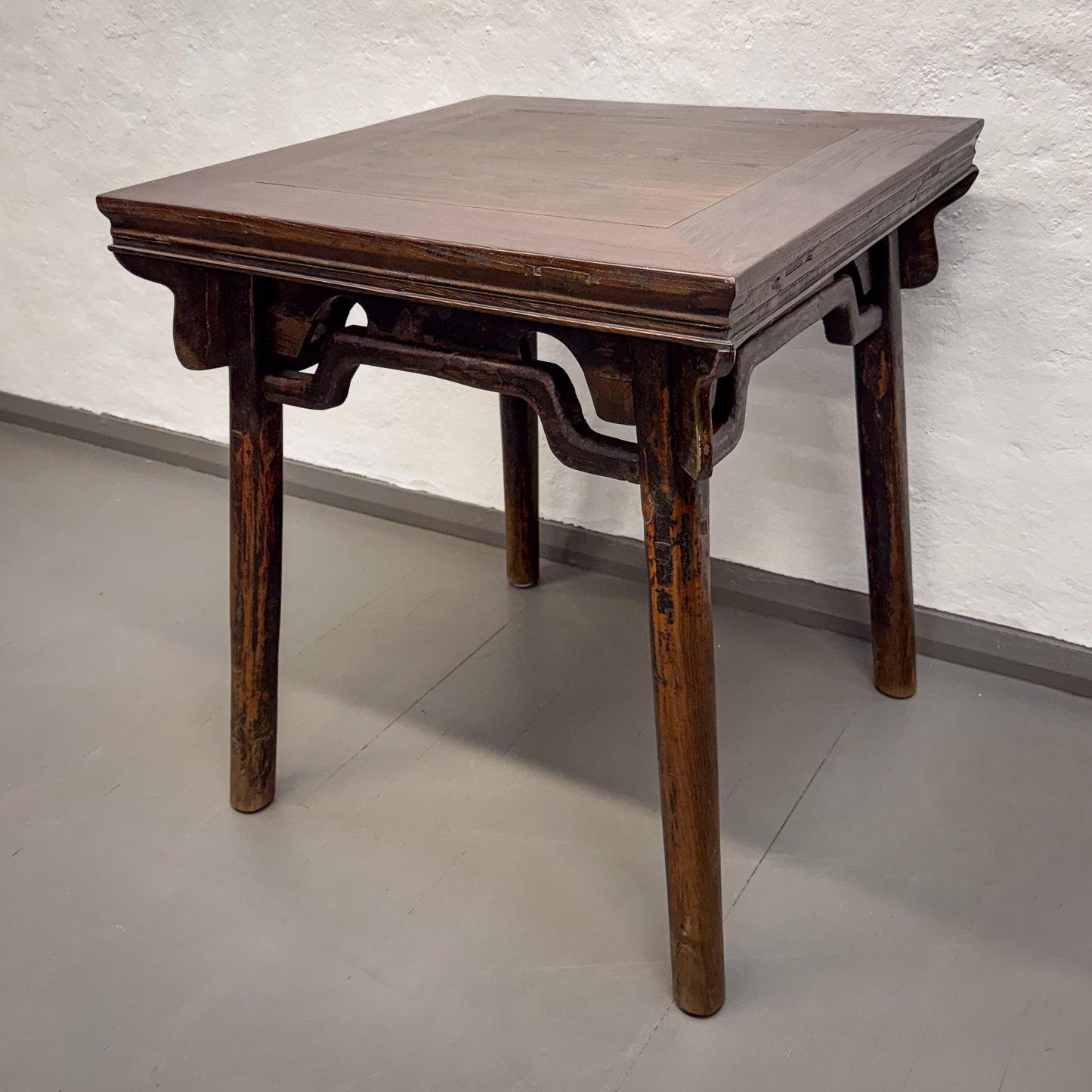 Wooden table with a textured surface on a plain floor and wall background