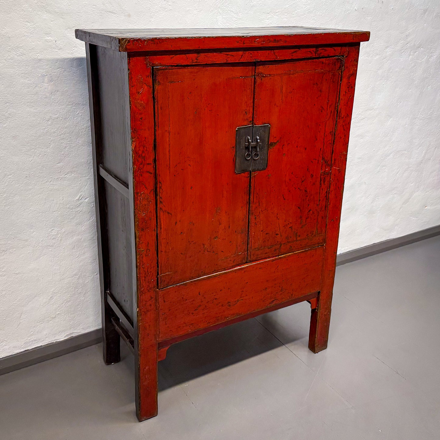 Red wooden cabinet with a gray base against a white wall