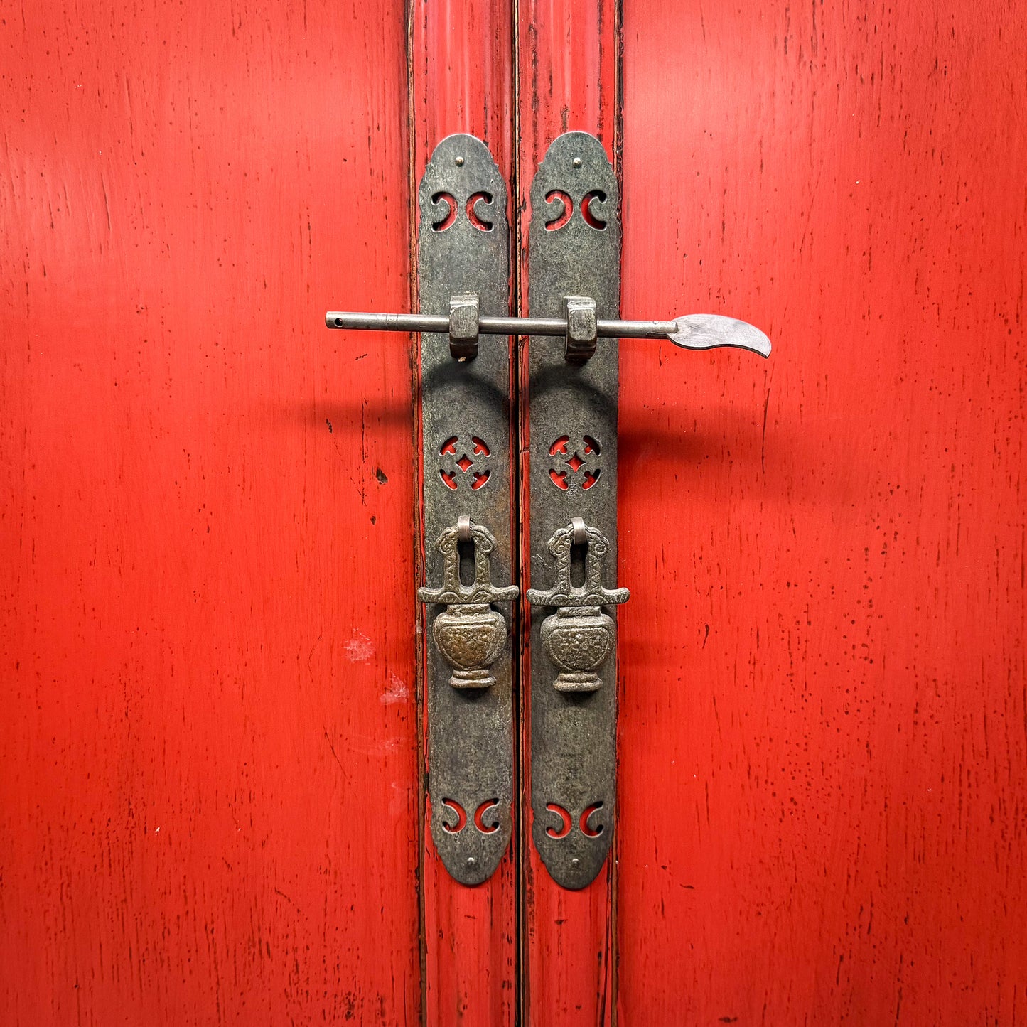 Decorative metal door handle on a red wooden door