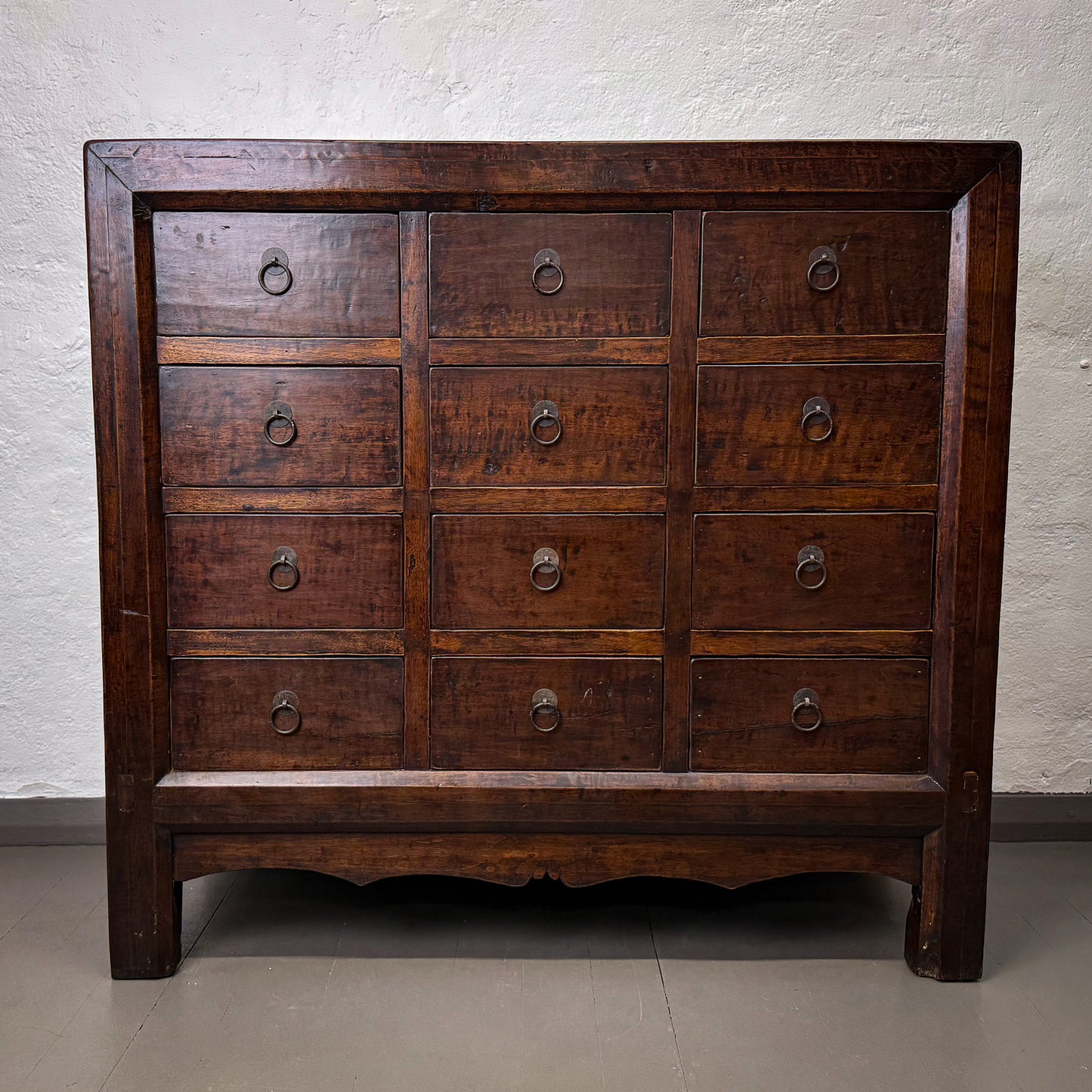Wooden dresser with multiple drawers against a plain wall